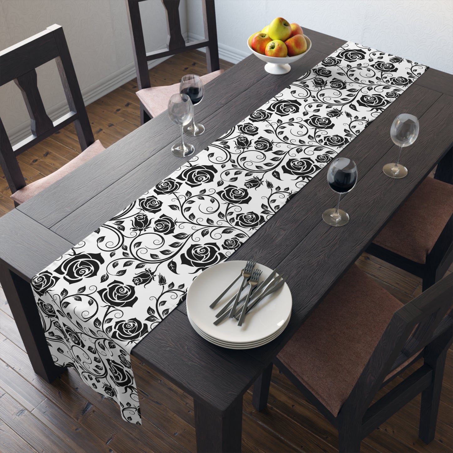 Dining table with a black and white floral table runner, plates, and glasses.