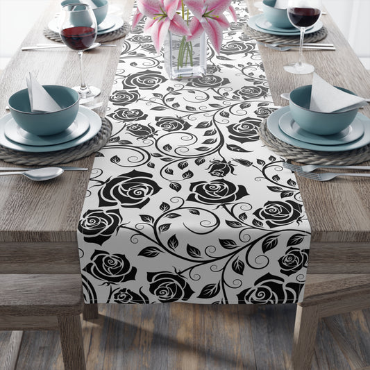Table setting with a black rose patterned table runner on a wooden table.