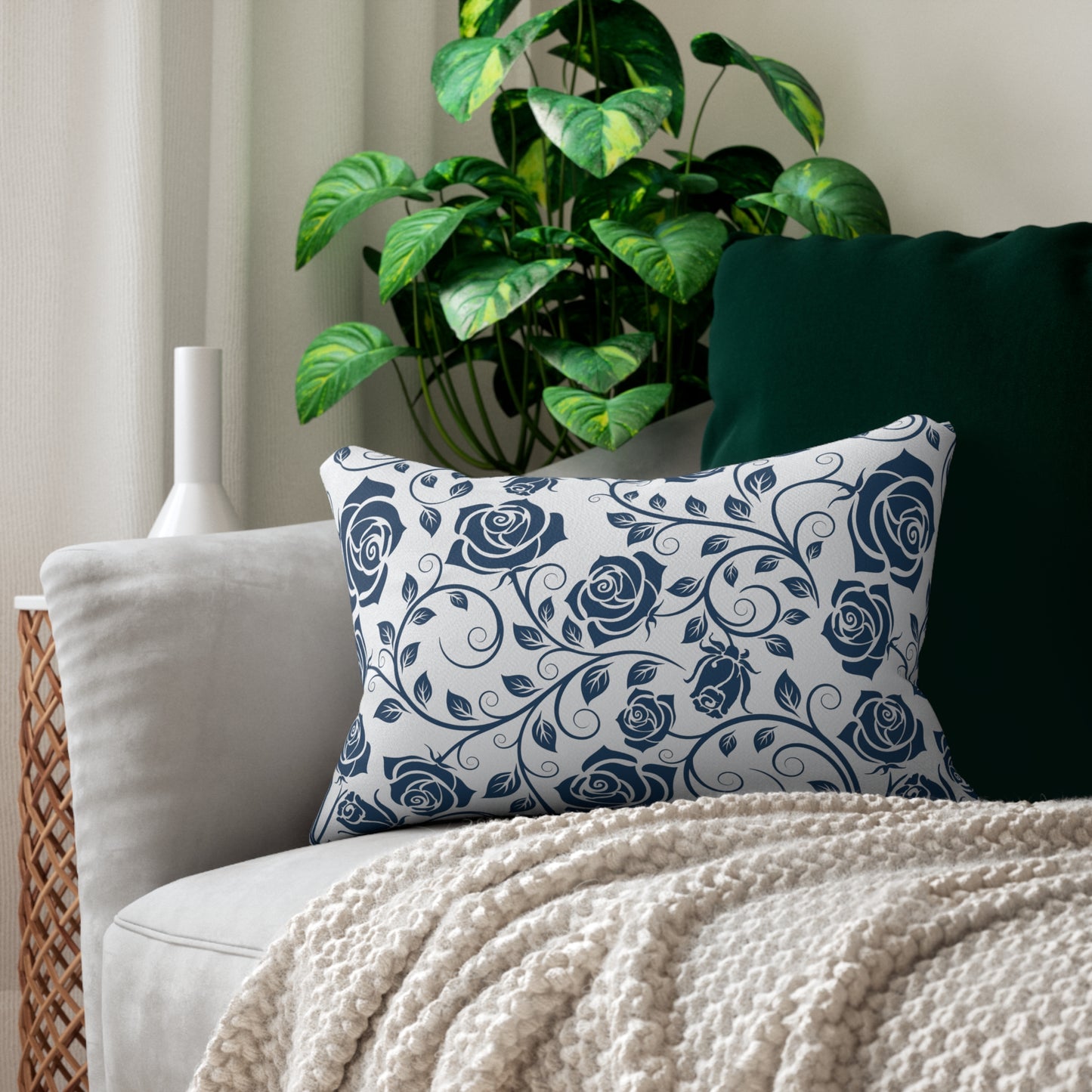 Decorative pillow with blue rose pattern on a sofa with a plant in the background