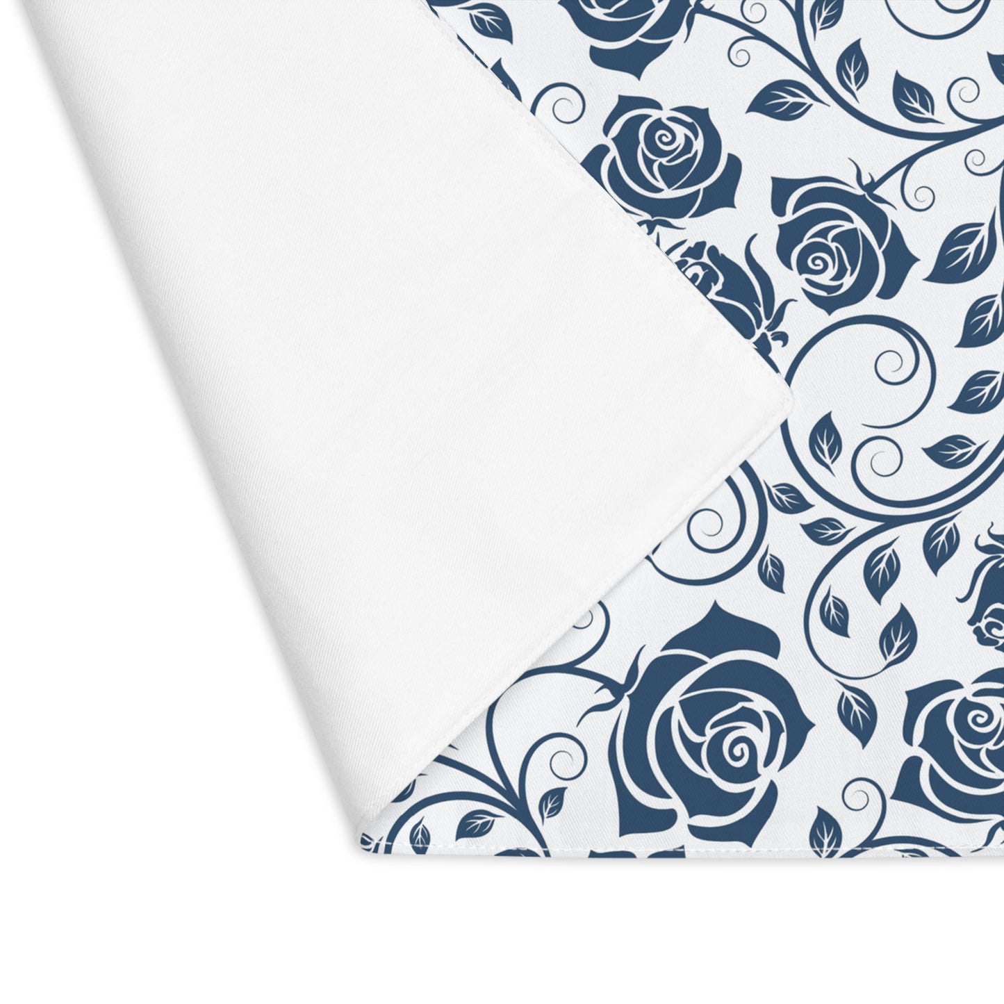 Placemat with blue floral rose pattern with corner folded over to reveal white backside