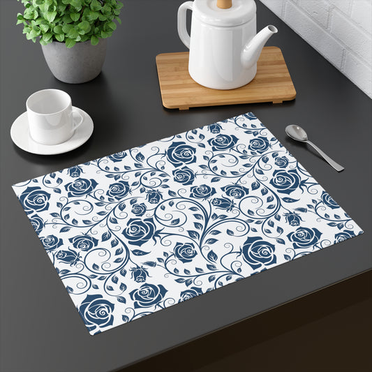 Placemat with blue rose pattern on a dark surface with tea set and plant.