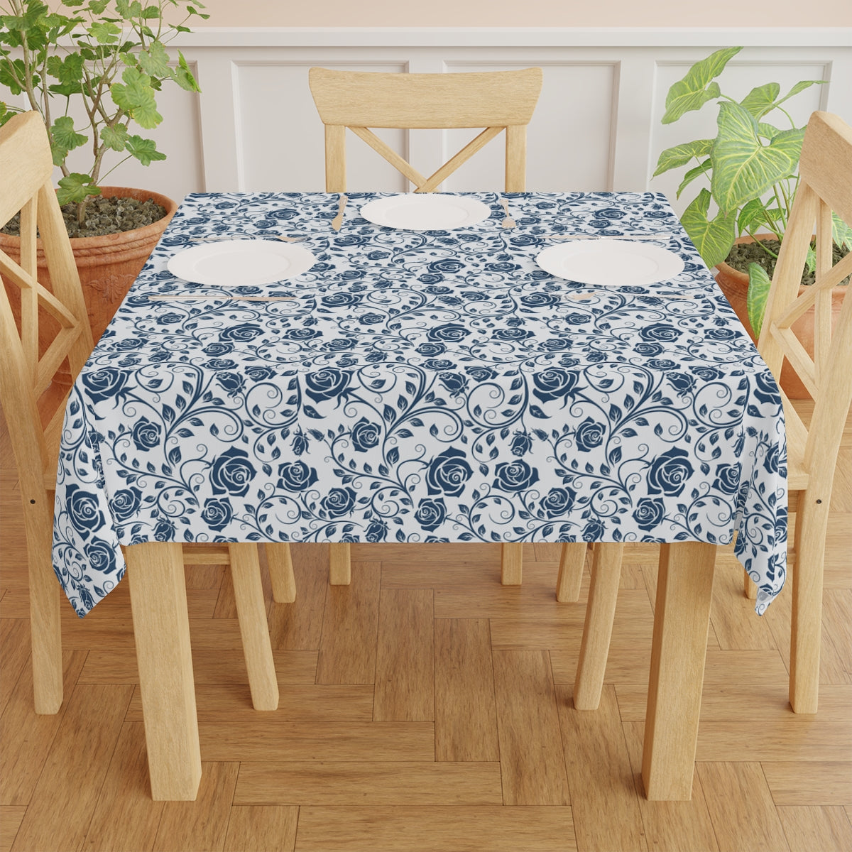Table with a blue and white floral patterned tablecloth on a wooden table and chairs.