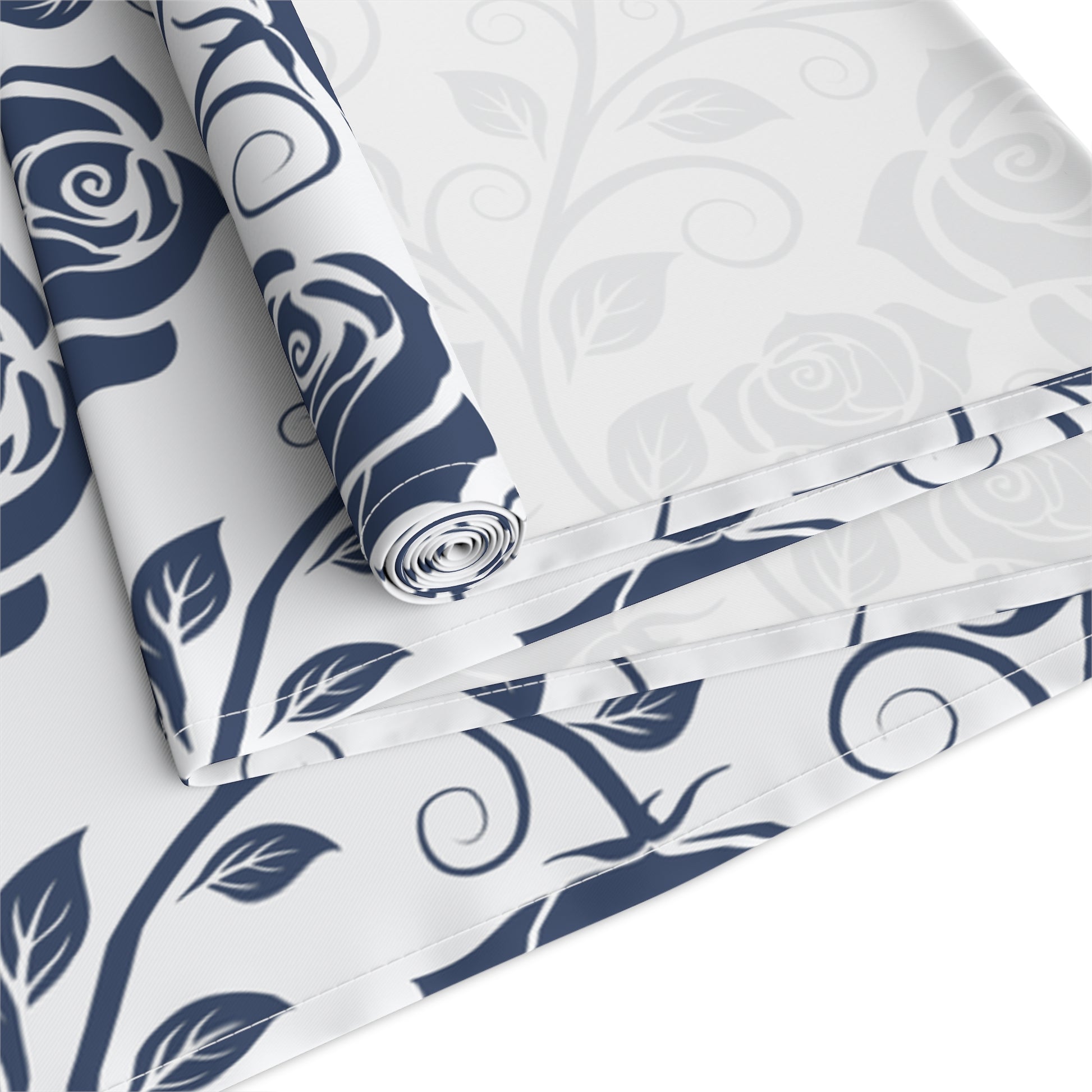 Table runner with blue and white floral pattern rolled up and folded on a white background