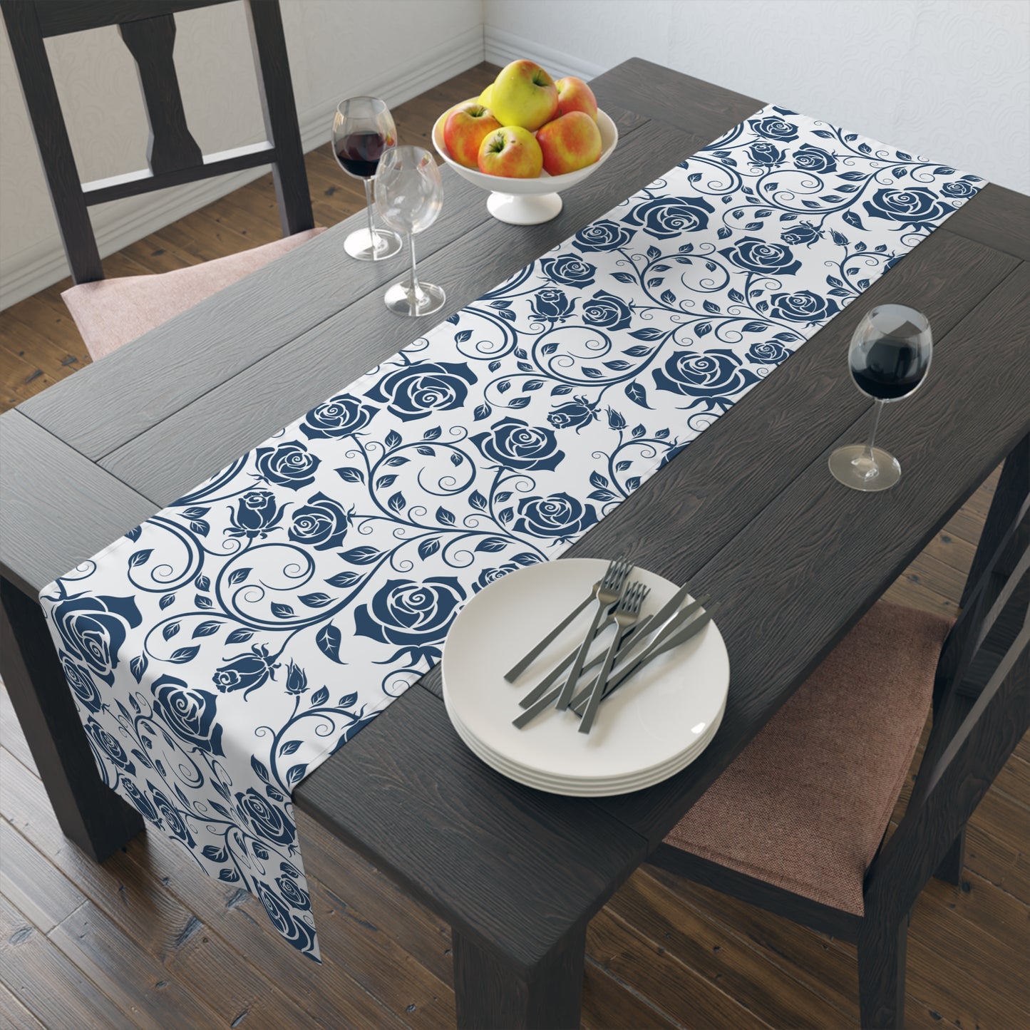 Dining table with a blue and white floral table runner, plates, and cutlery.