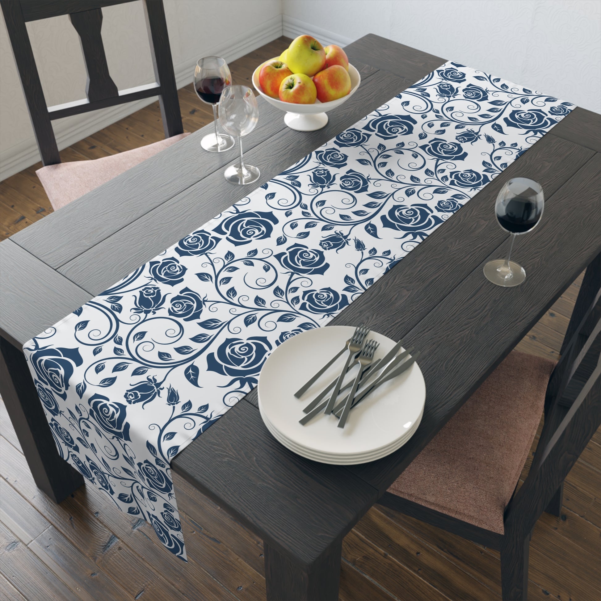 Dining table with a blue and white floral table runner, plates, and cutlery.