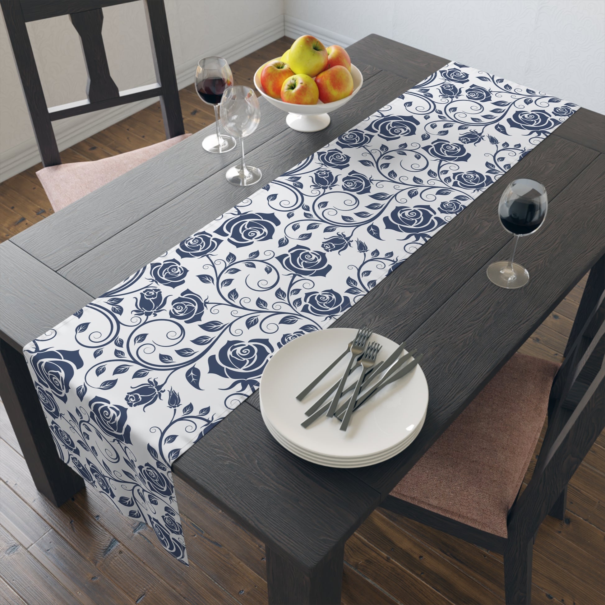 Dining table set with a blue and white floral table runner, plates, and cutlery.