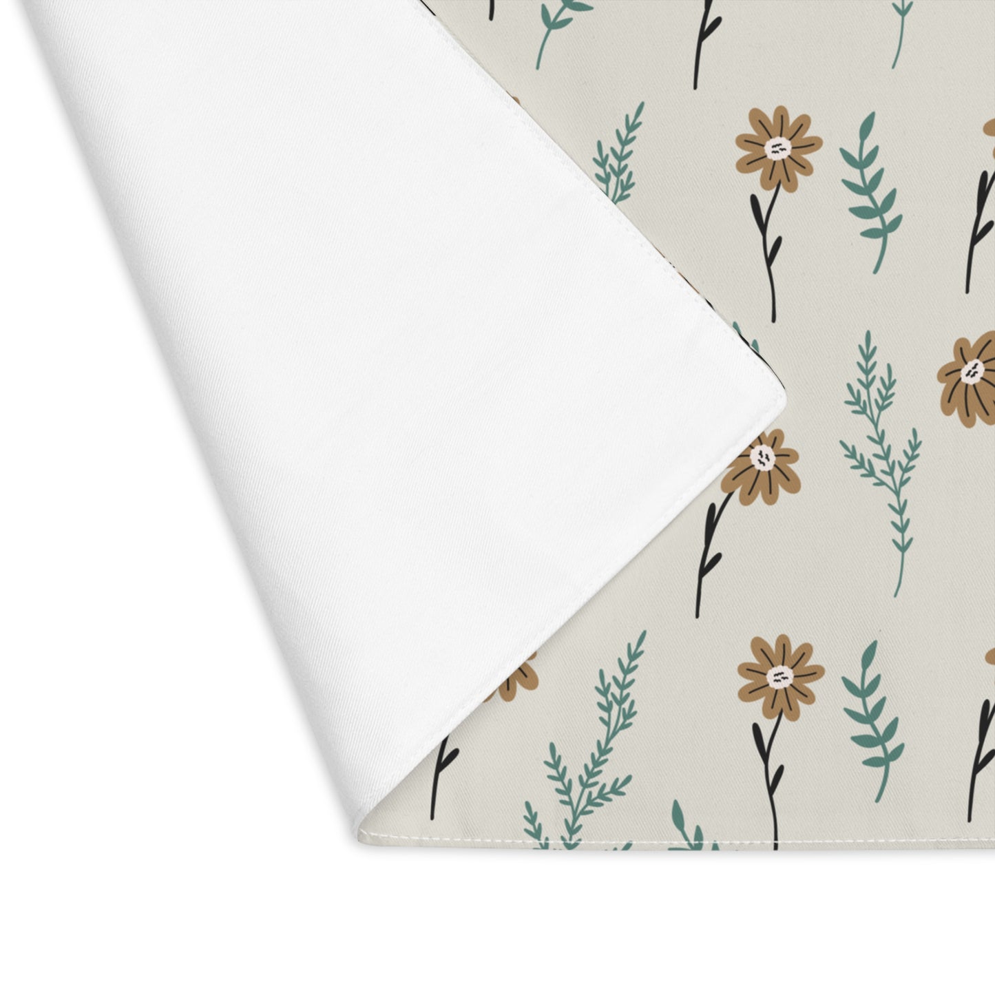 Corner folded over to view back of our Brown Camomile placemat with brown and gray cotton twill fabric with small flowers and leaves on a beige background on a white background