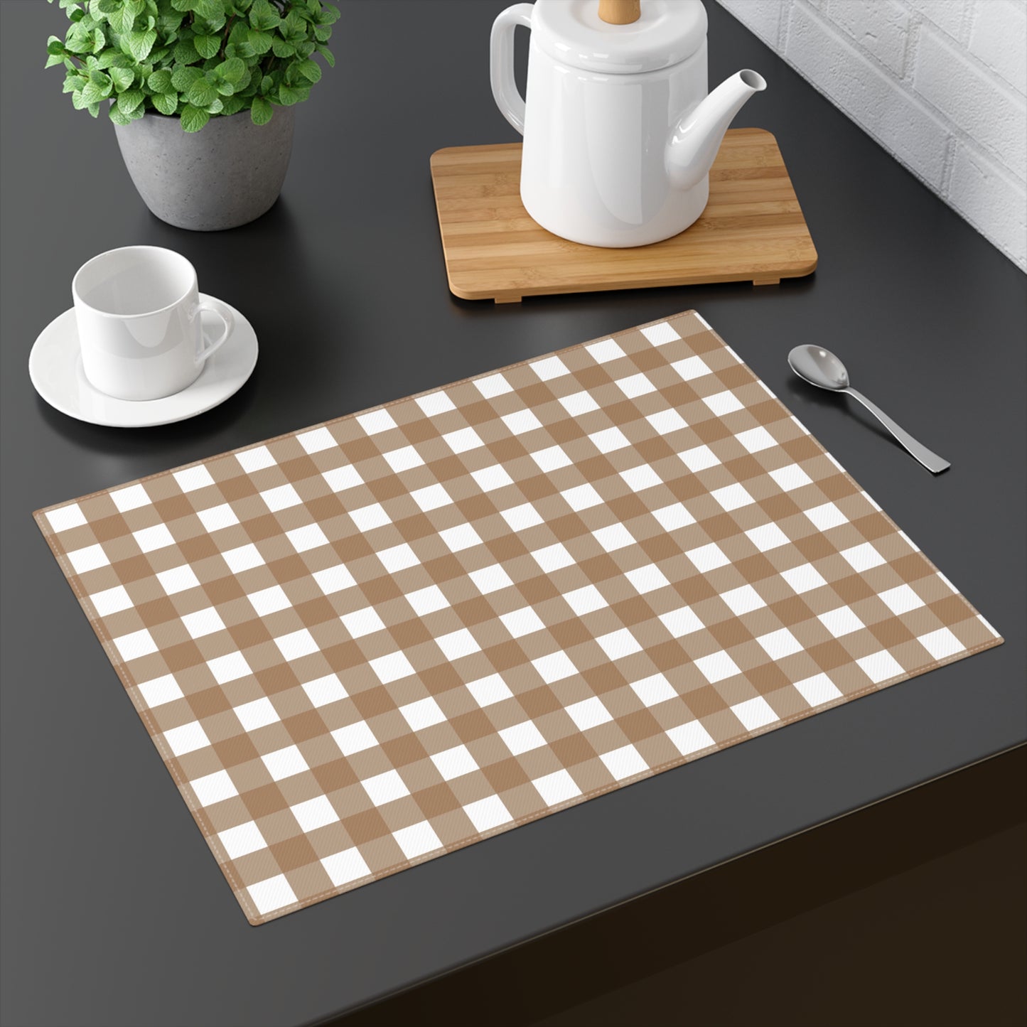 Our Brown Gingham placemat  with brown and white checkered pattern on a dark surface with a teapot, cup, and spoon.