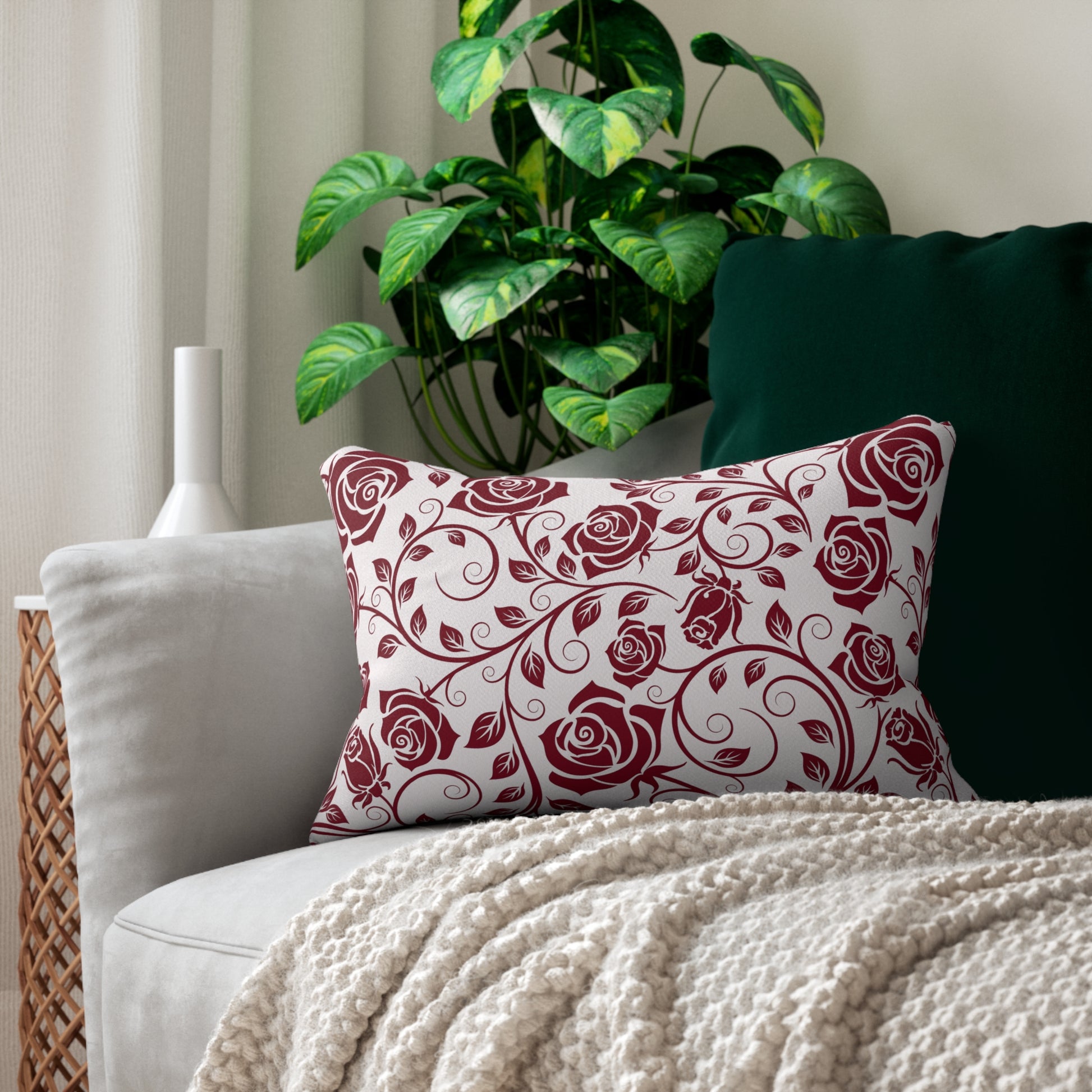 Decorative pillow with burgundy red floral pattern on a couch with a plant in the background