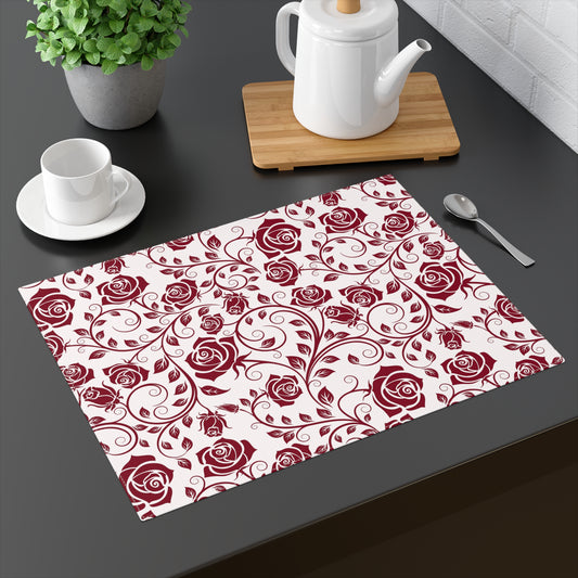 Placemat with red rose pattern on a dark surface with tea set and plant.
