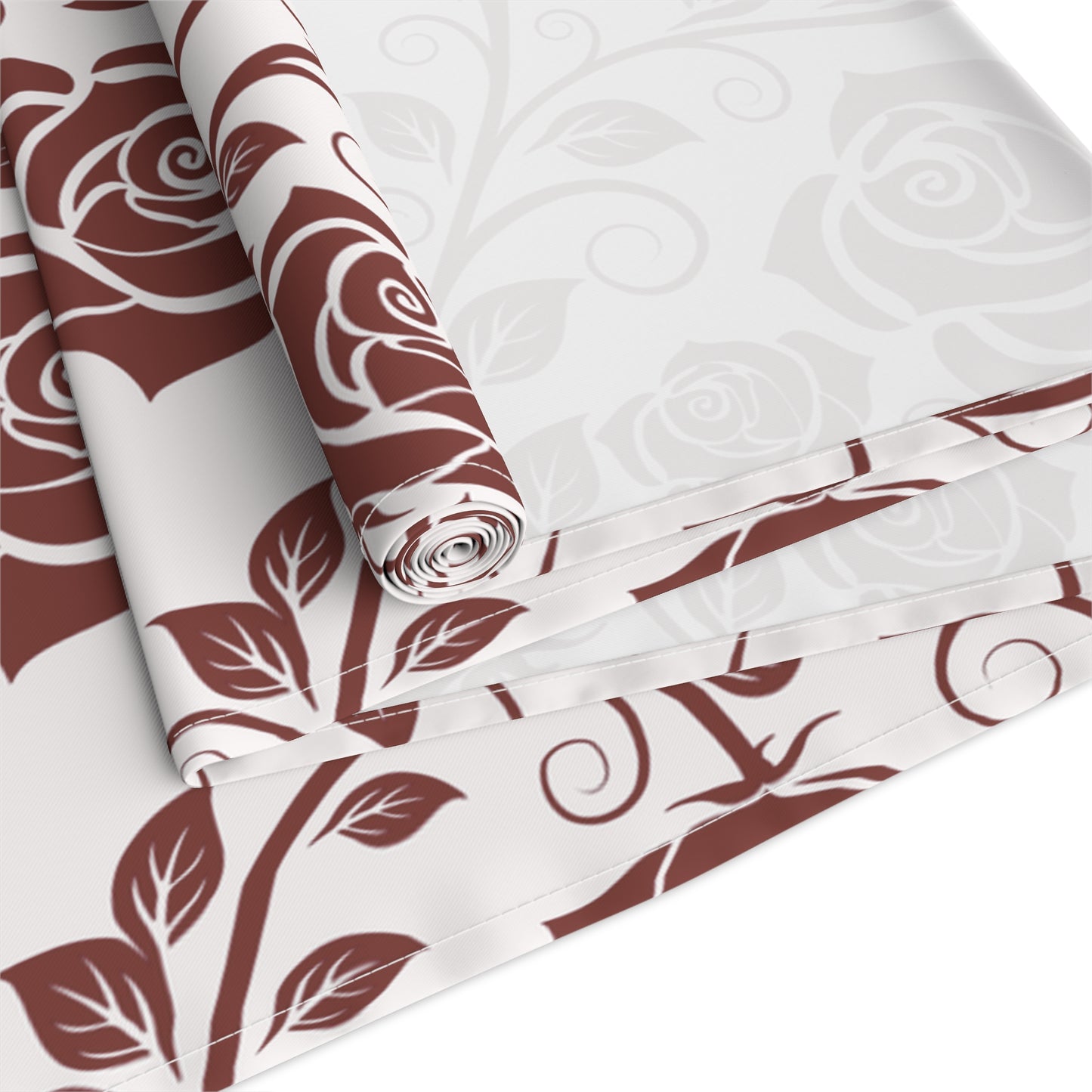 Table runner with burgundy floral pattern rolled up and folded on a white background