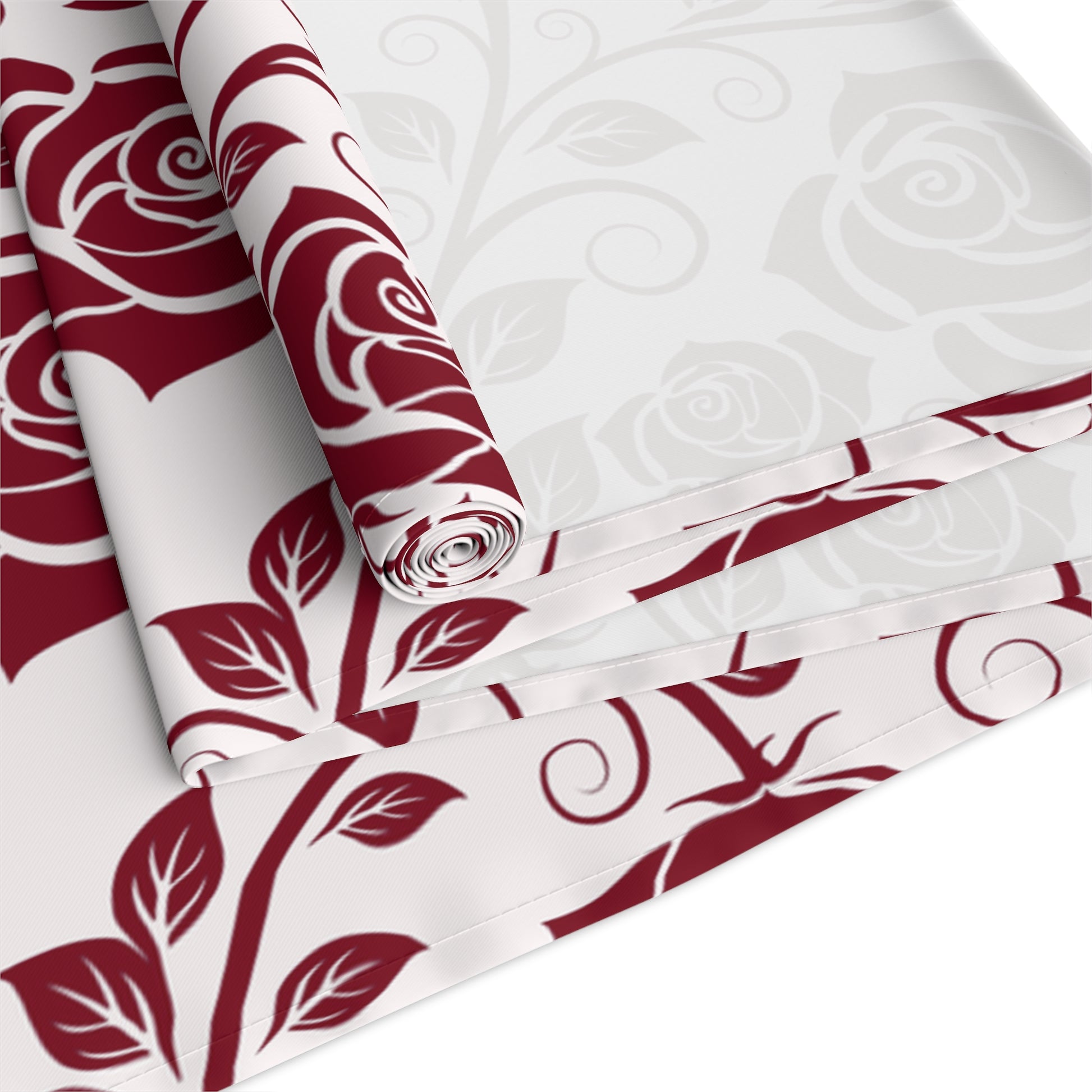 Red floral patterned table runner rolled up and folded on a white background