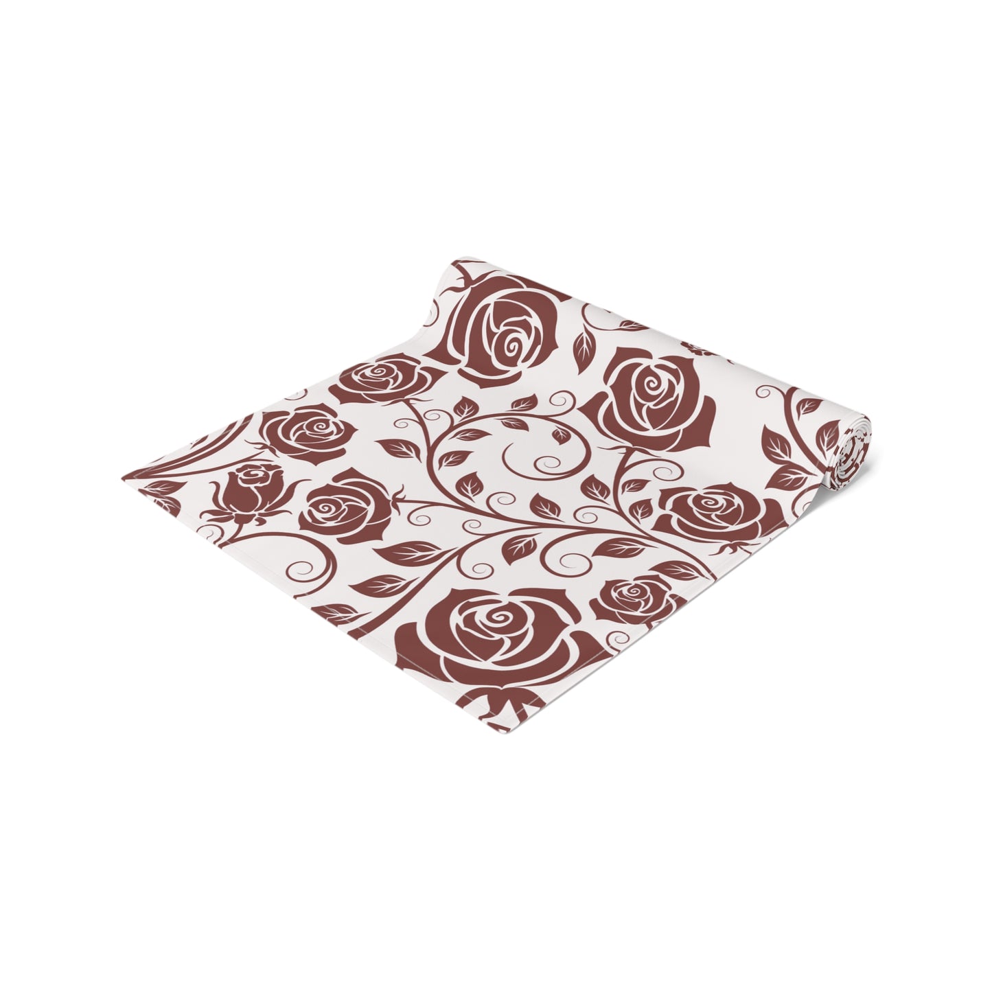 Table runner with burgundy floral patterned fabric with red roses rolled up on a white background