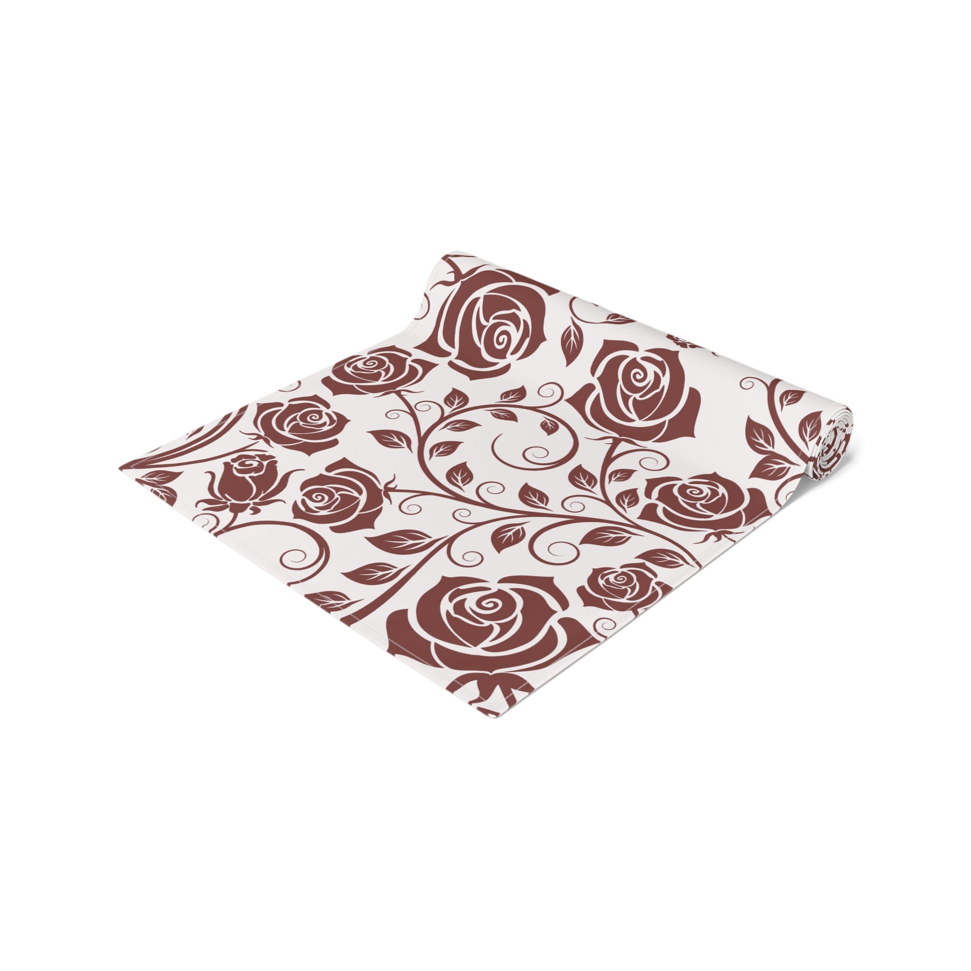 Table runner with burgundy floral patterned fabric with red roses rolled up on a white background