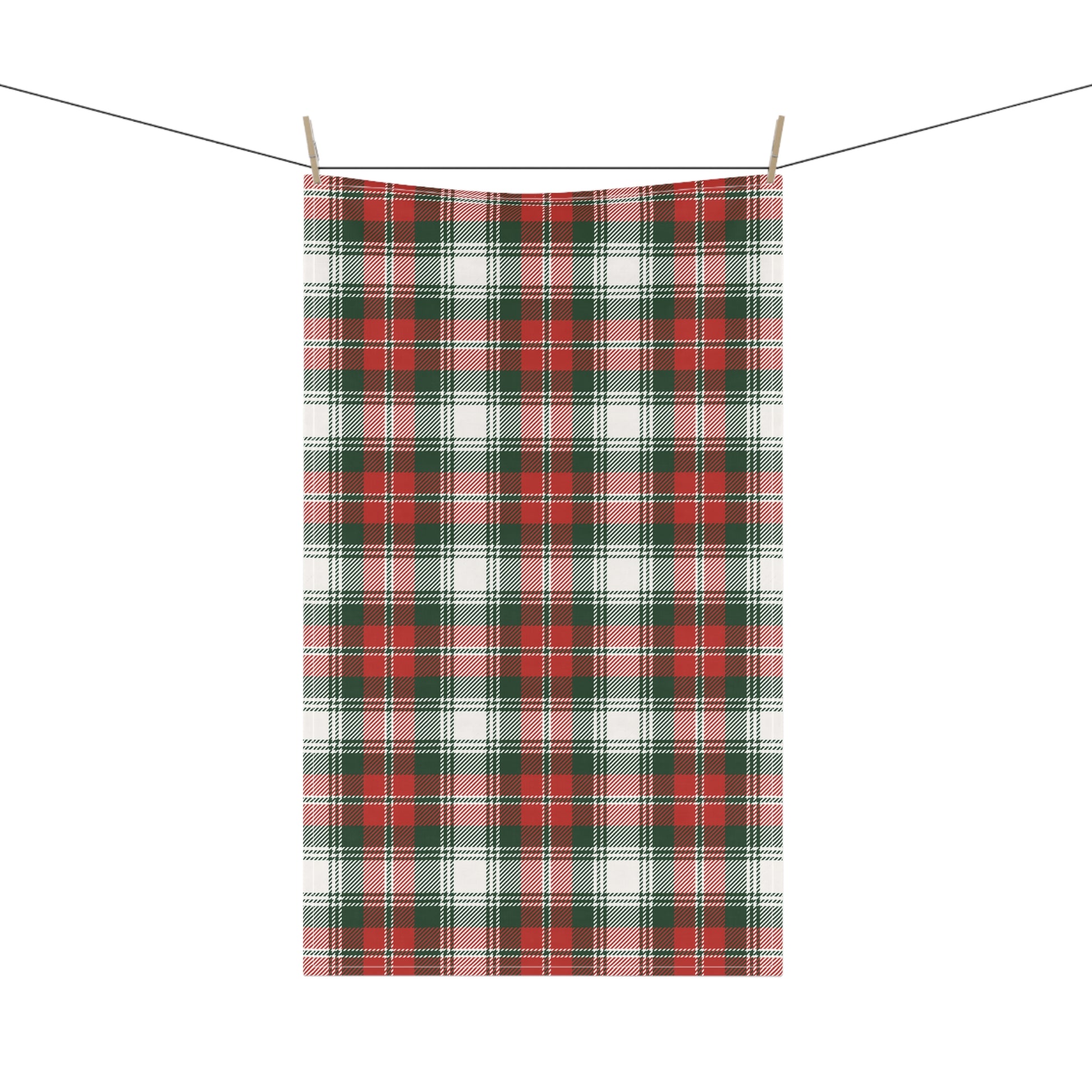 Plaid greena and red tea towel hanging on a clothesline with wooden pegs against a white background