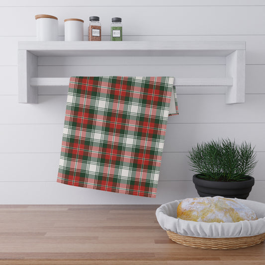 Plaid green and red towel hanging on a rack above a wooden surface with a plant and basket.