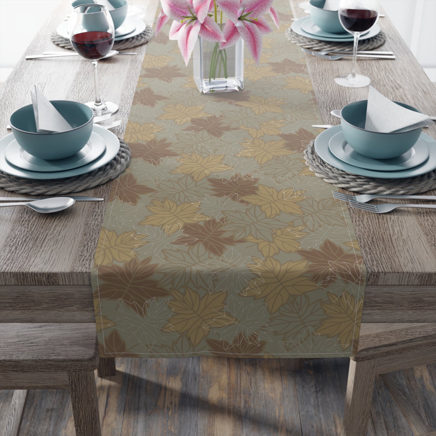Table setting with a fall leaf-patterned table runner on a wooden table.