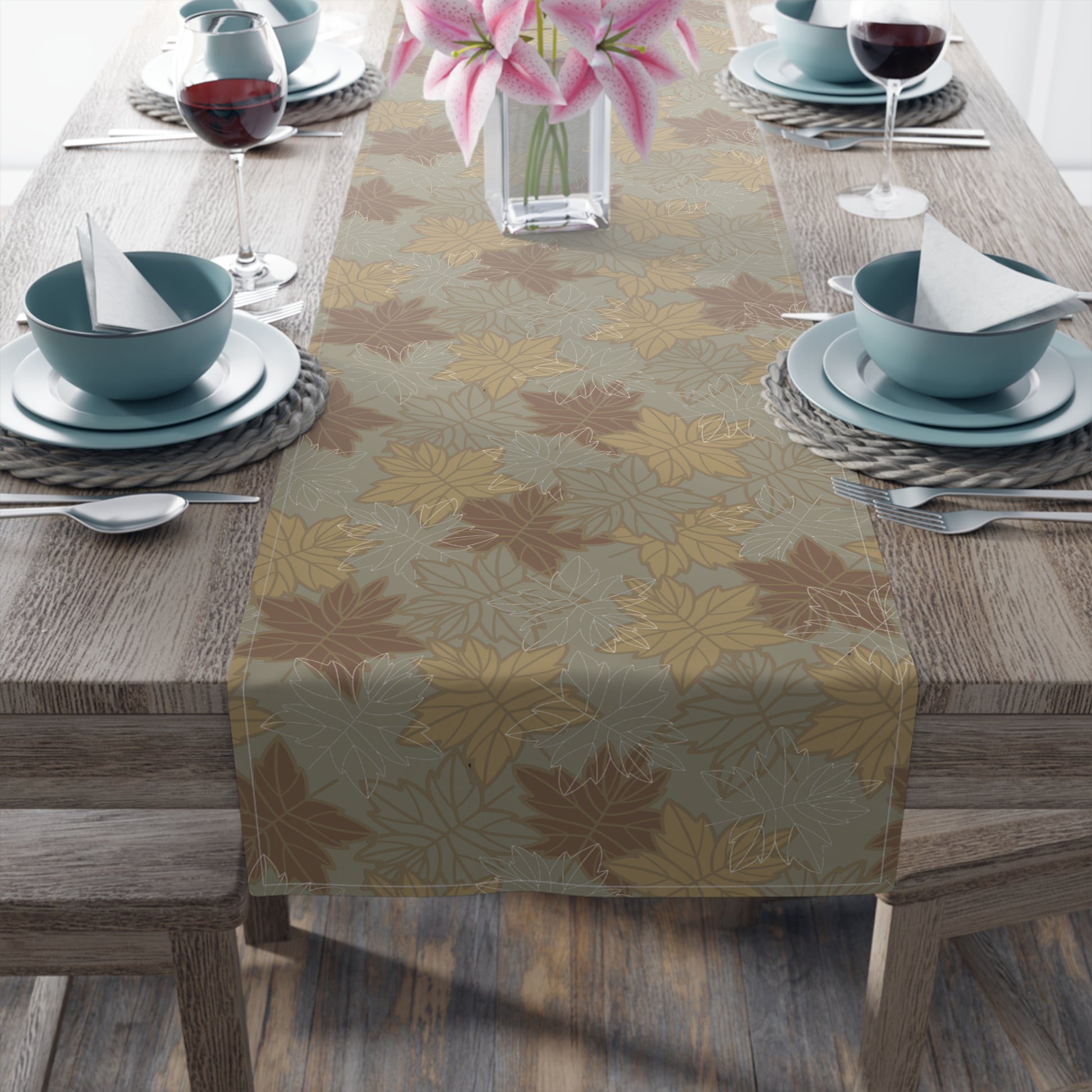 Table setting with a leaf-patterned cotton table runner on a wooden table.