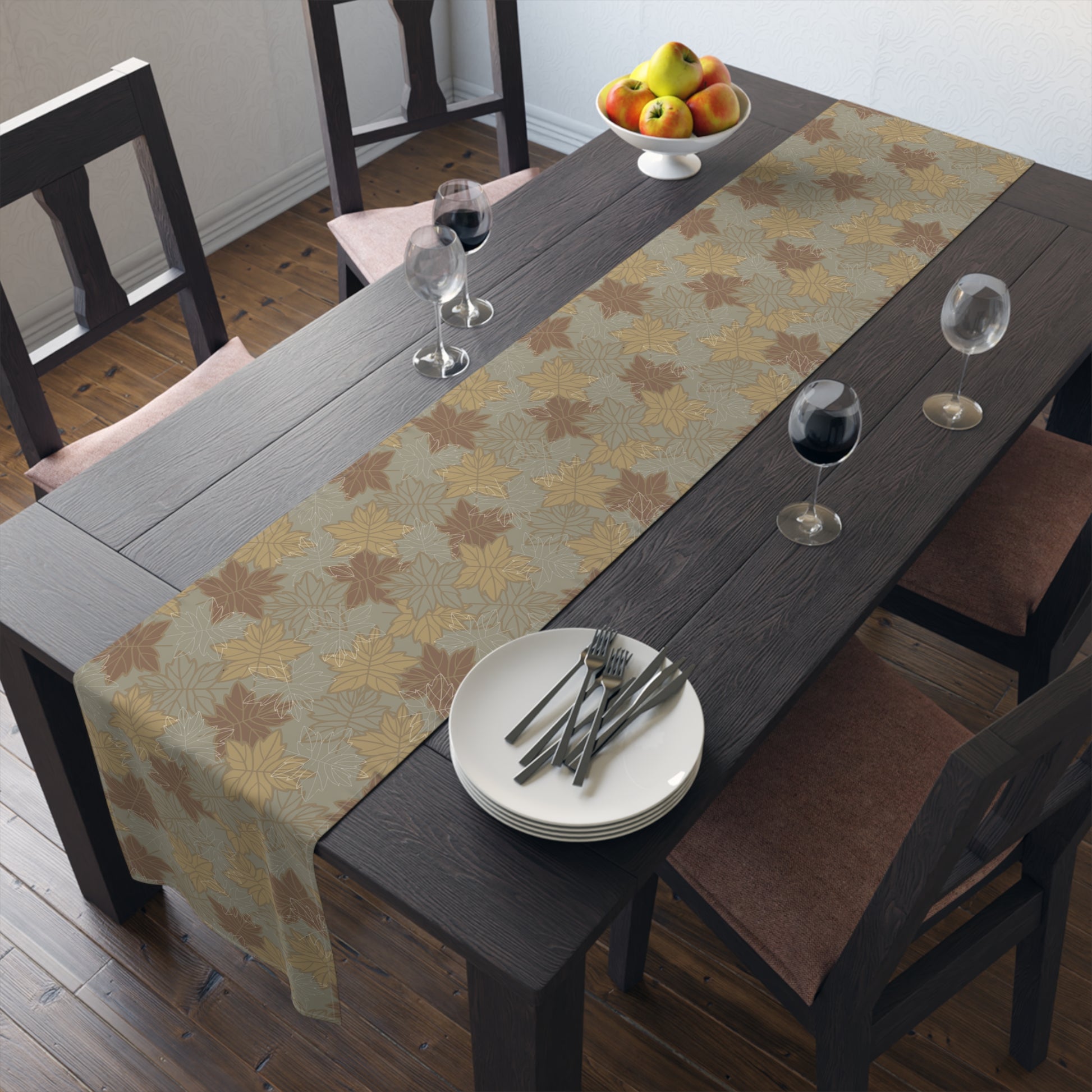 Dining table set with a leaf-patterned table runner, plates, and glasses.