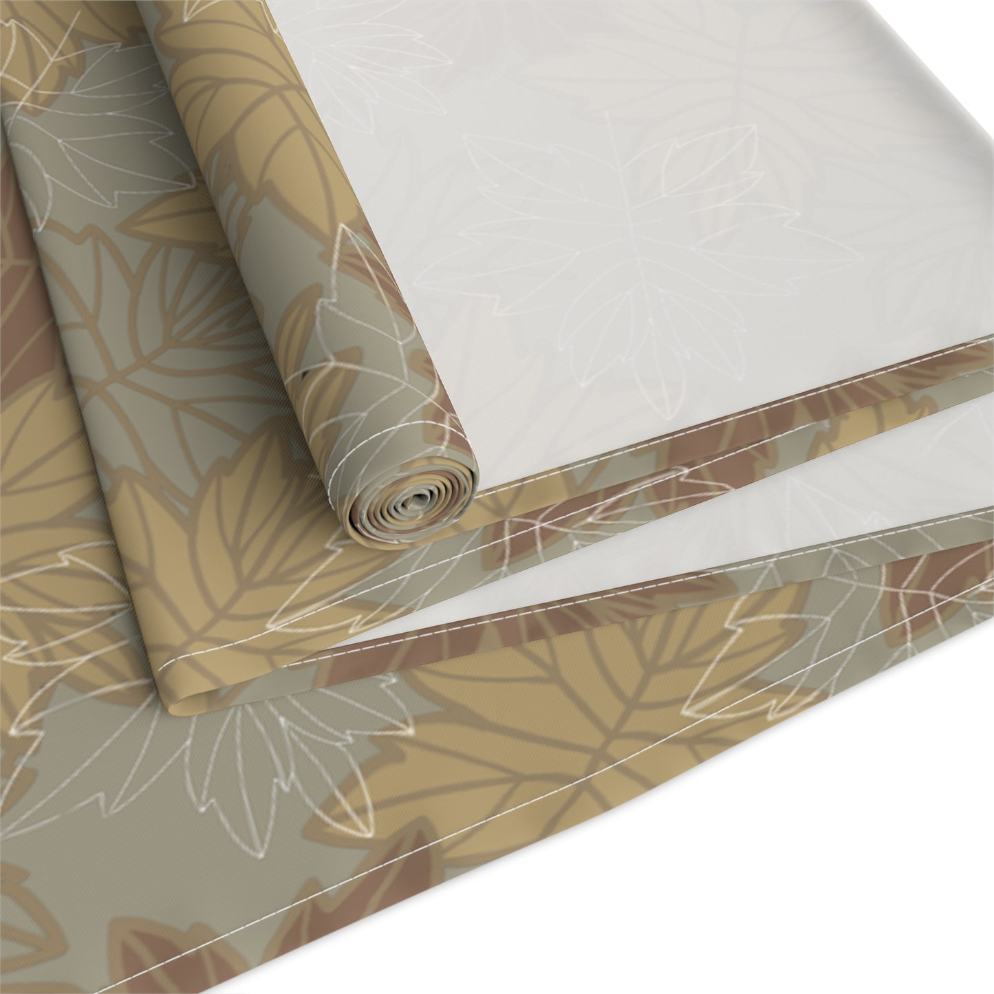 Roll of  cotton table runner with leaf pattern on a white background