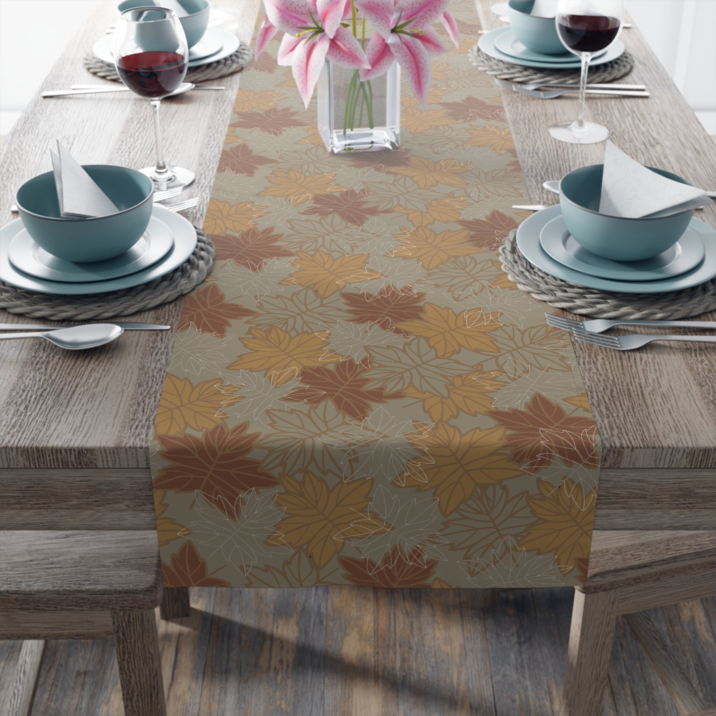 Table setting with a fall-leaf themed table runner on a wooden table.
