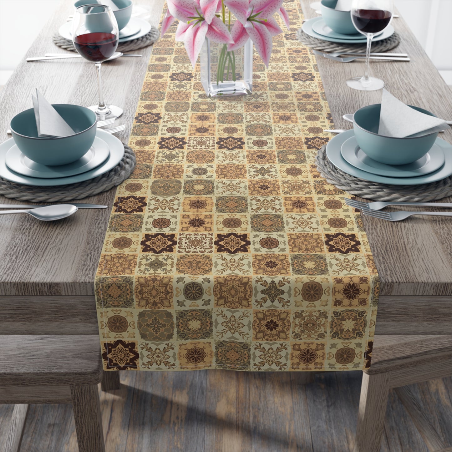 Our Fall Flowers Mosaic table runner has a brown, green and gold floral square geometric pattern. This table runner is on a wooden table with dining setup