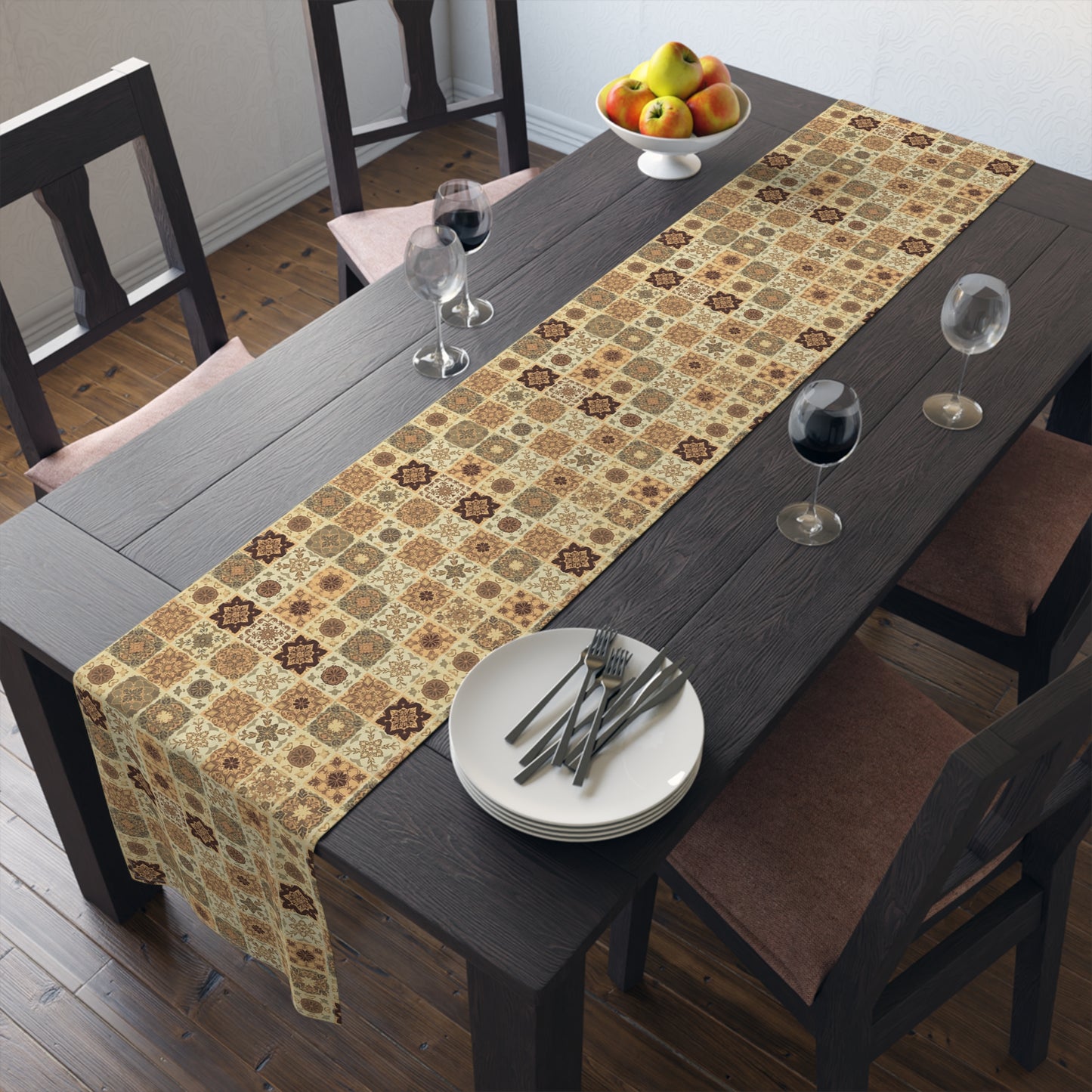 Our Fall Flowers Mosaic table runner has a brown, green and gold floral square geometric pattern. This table runner is on a dining table with plates, and glasses.