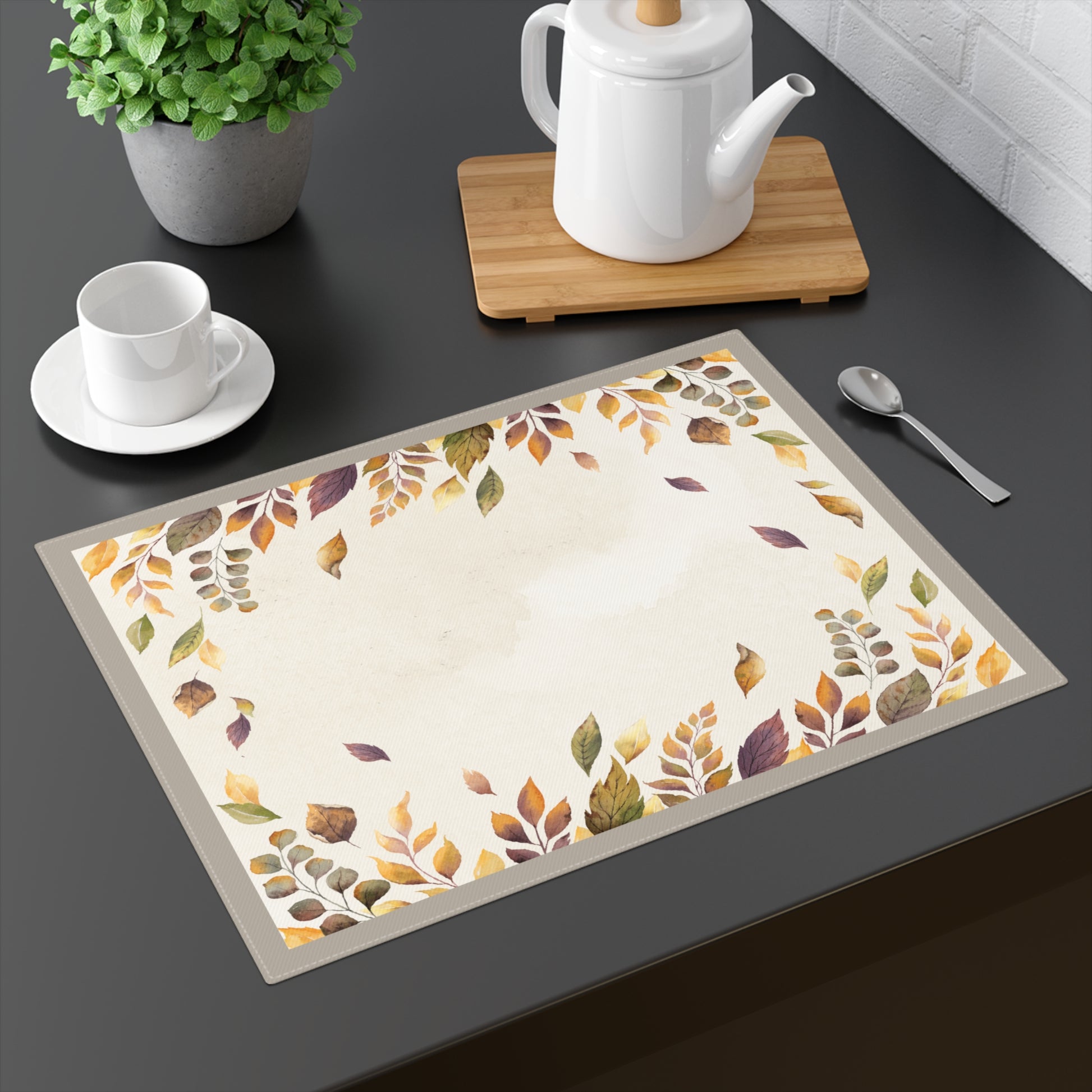 Placemat with autumn leaf pattern on a dark surface with tea set.