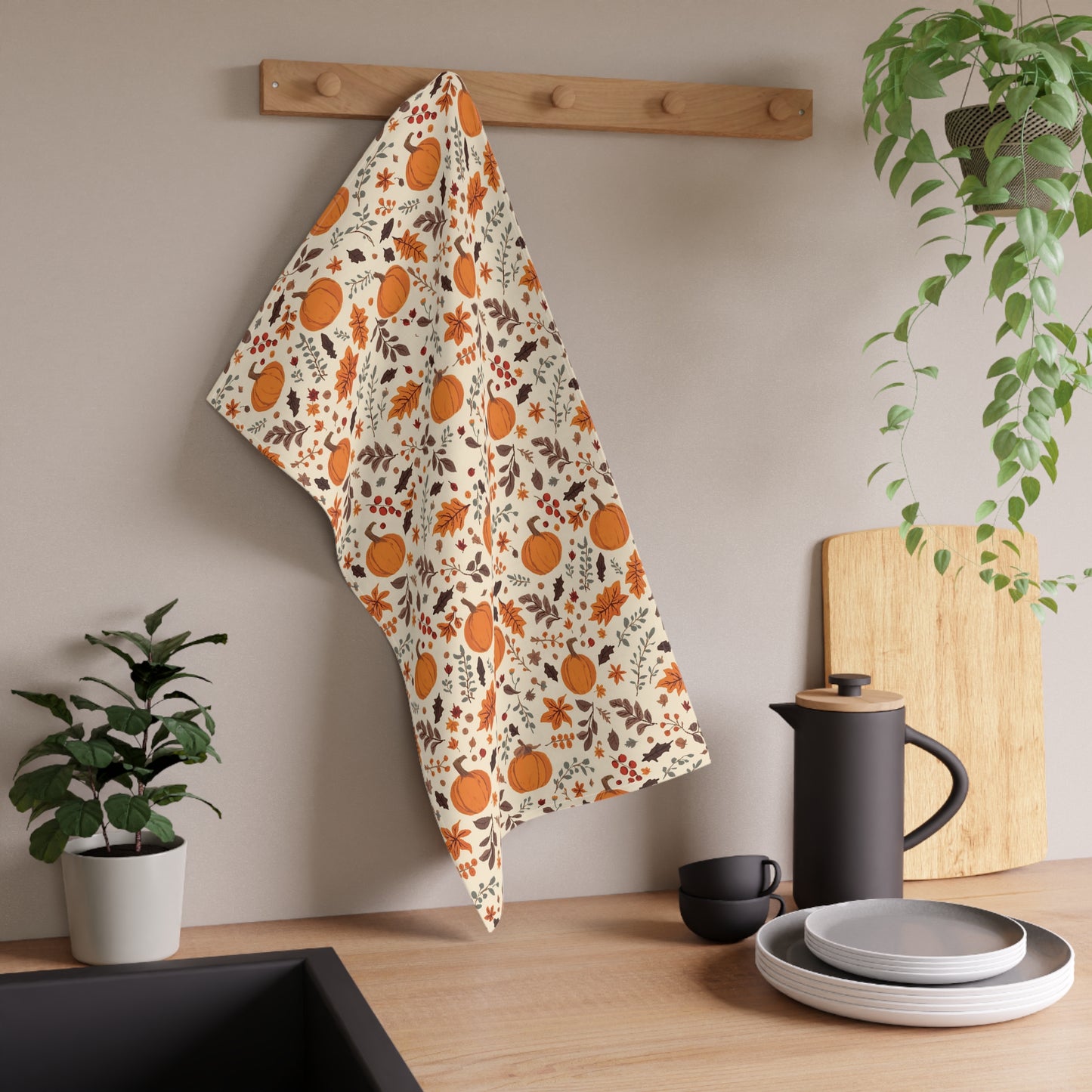 Decorative towel with pumpkin pattern hanging on a wooden rack in a kitchen setting.