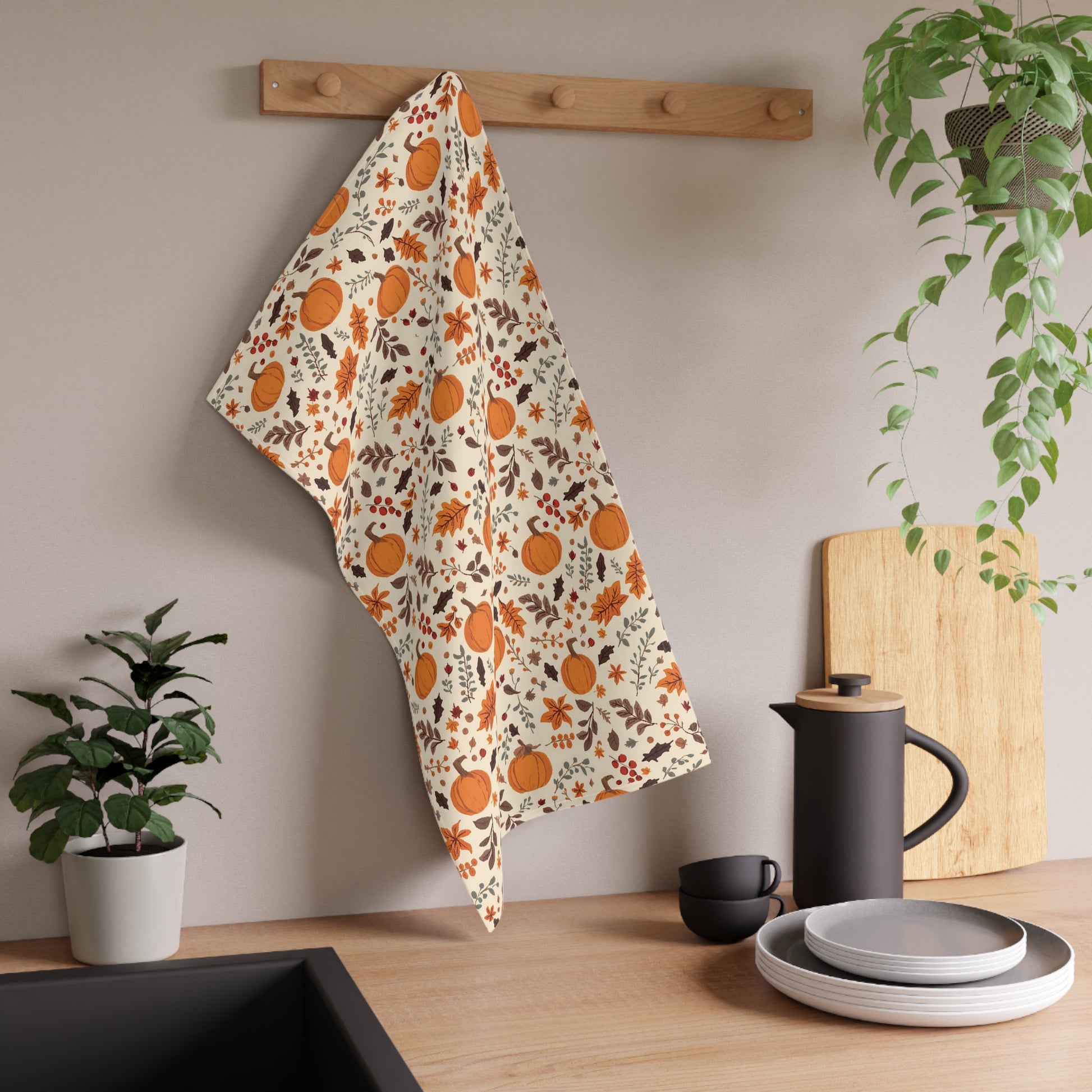 Decorative towel with pumpkin pattern hanging on a wooden rack in a kitchen setting.