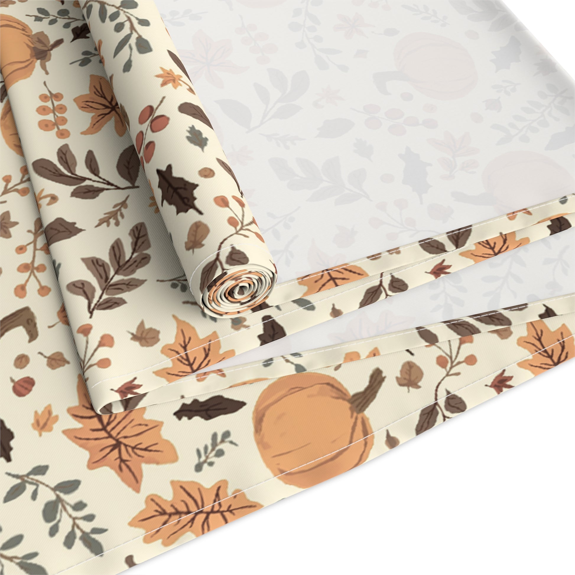 Fall Leaves and Pumpkins table runner has brown and orange fall leaves with orange pumpkins with beige background printed on the table runner that is rolled up and folded on a white background.