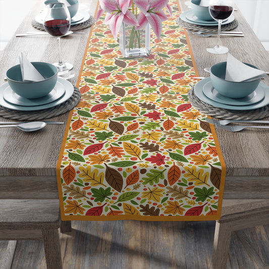 Fall Leaves cotton twill table runner on table setting with a colorful leaf-patterned table runner on a wooden table.