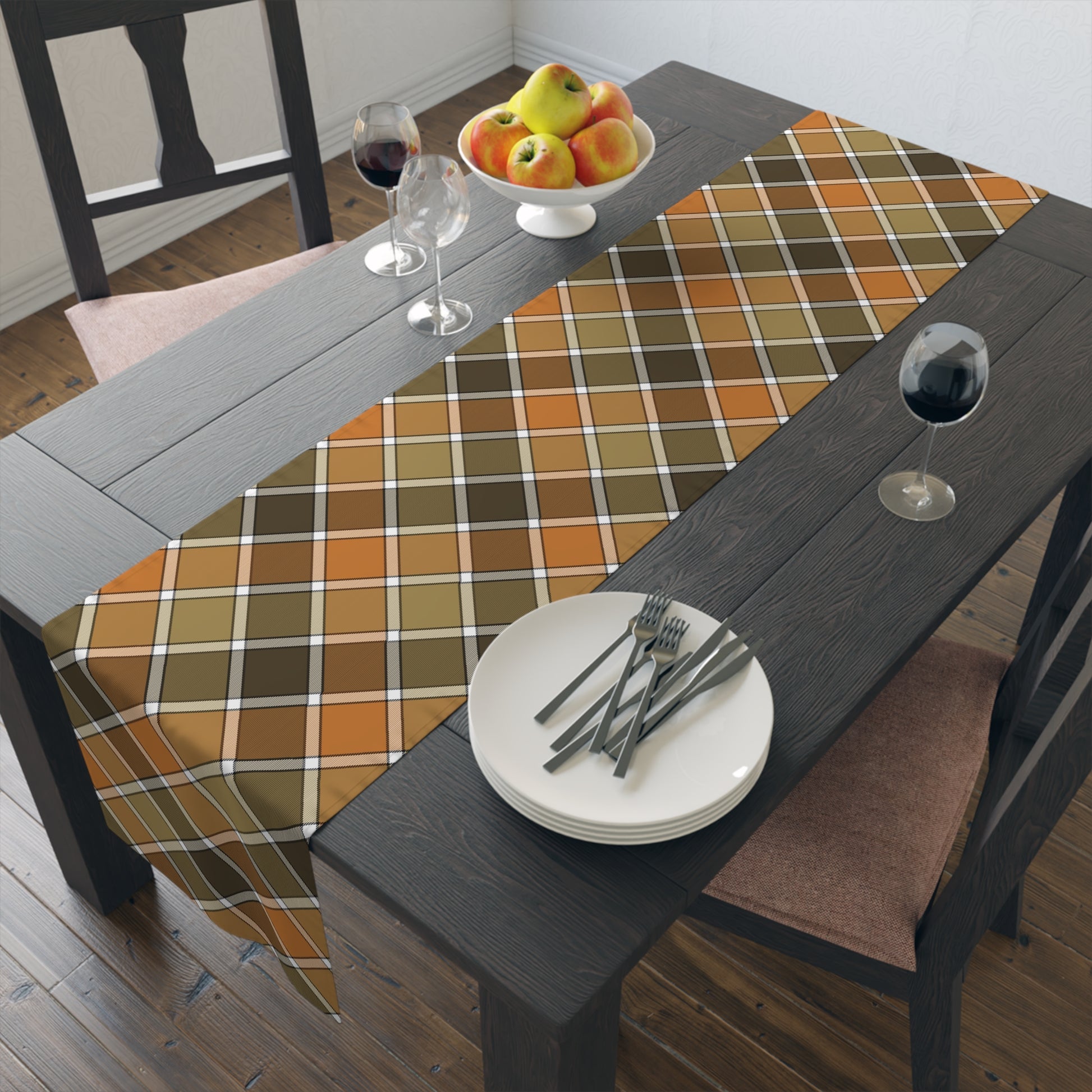 Our Fall Plaid table runner has brown, green, orange plaid patterned colors. The table runner is on a dining table with plates, forks, and a fruit bowl.