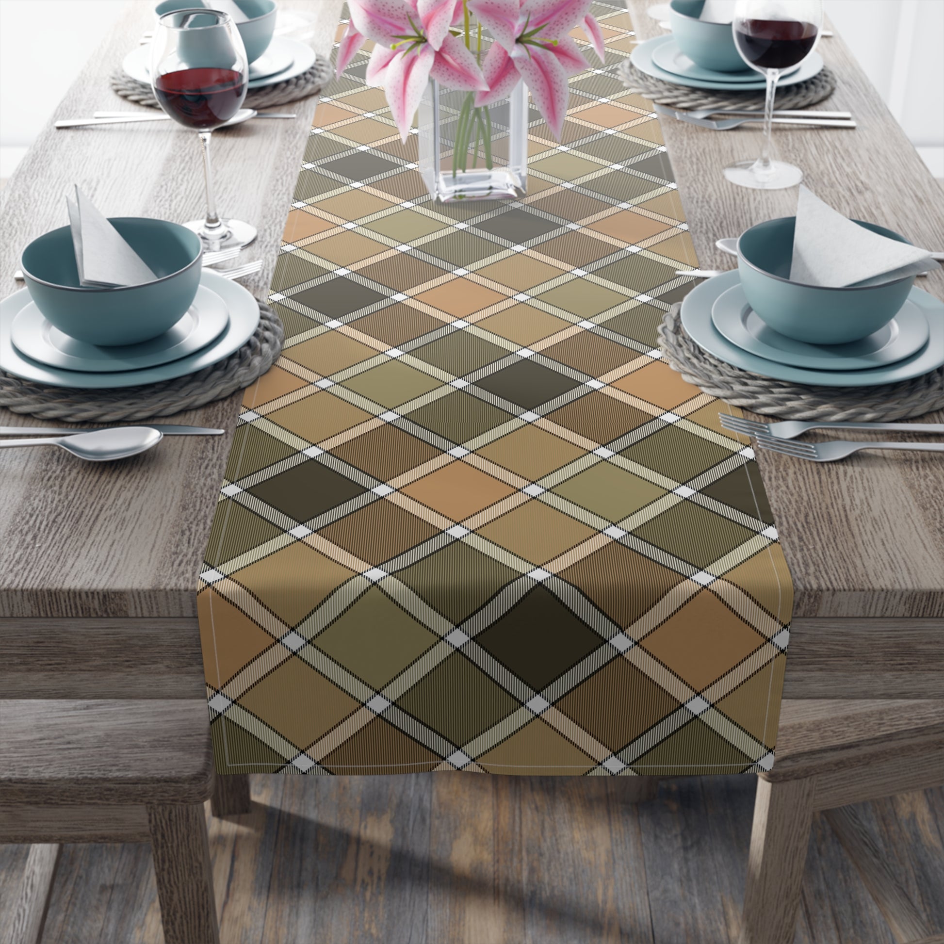 Our cotton twill Fall Plaid table runner has brown, green, orange plaid patterned colors. The table runner is on a table with blue dishes and a flower vase.