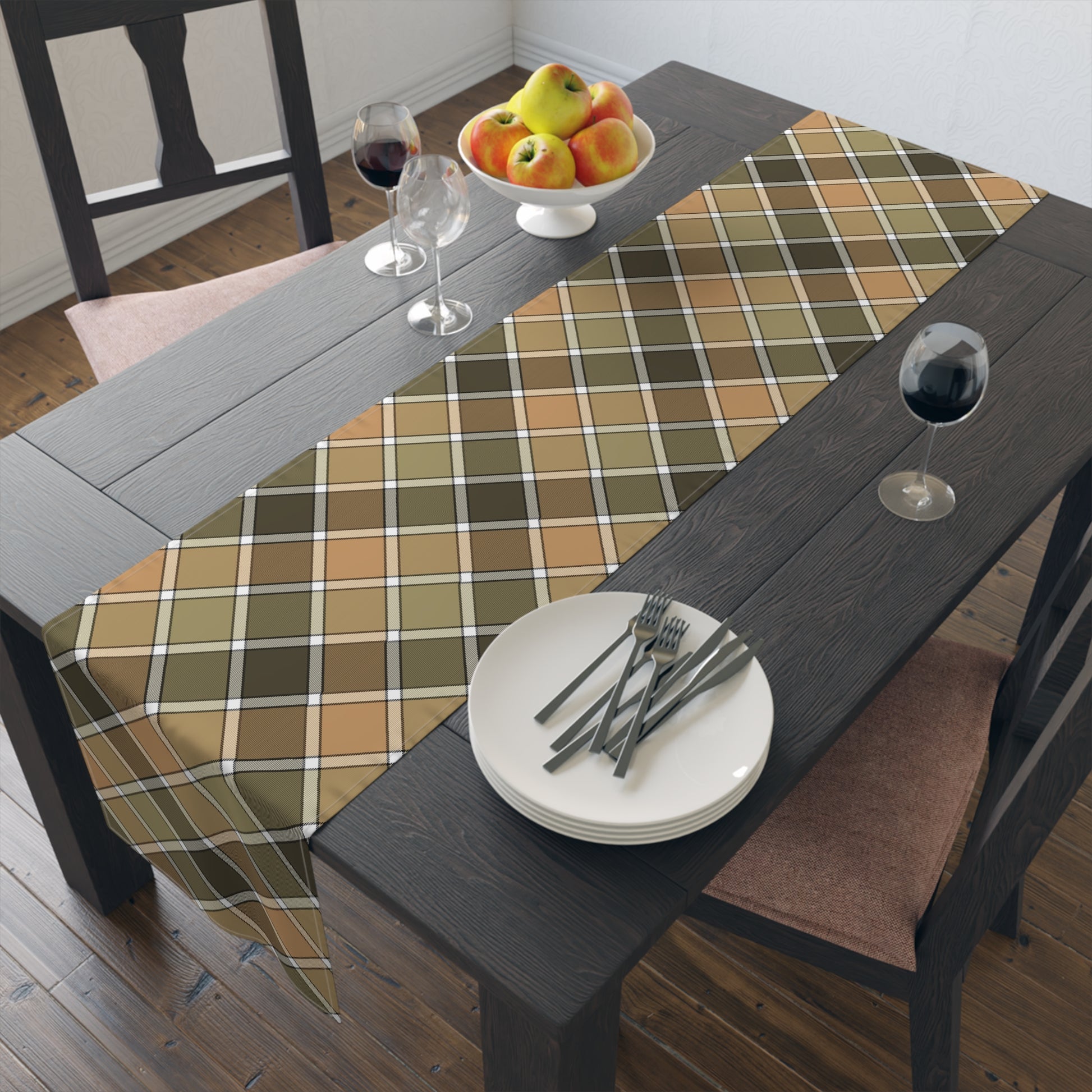Our Fall Plaid table runner has brown, green, orange plaid patterned colors. The table runner is on a dining table with plates, forks, and a bowl of fruit.