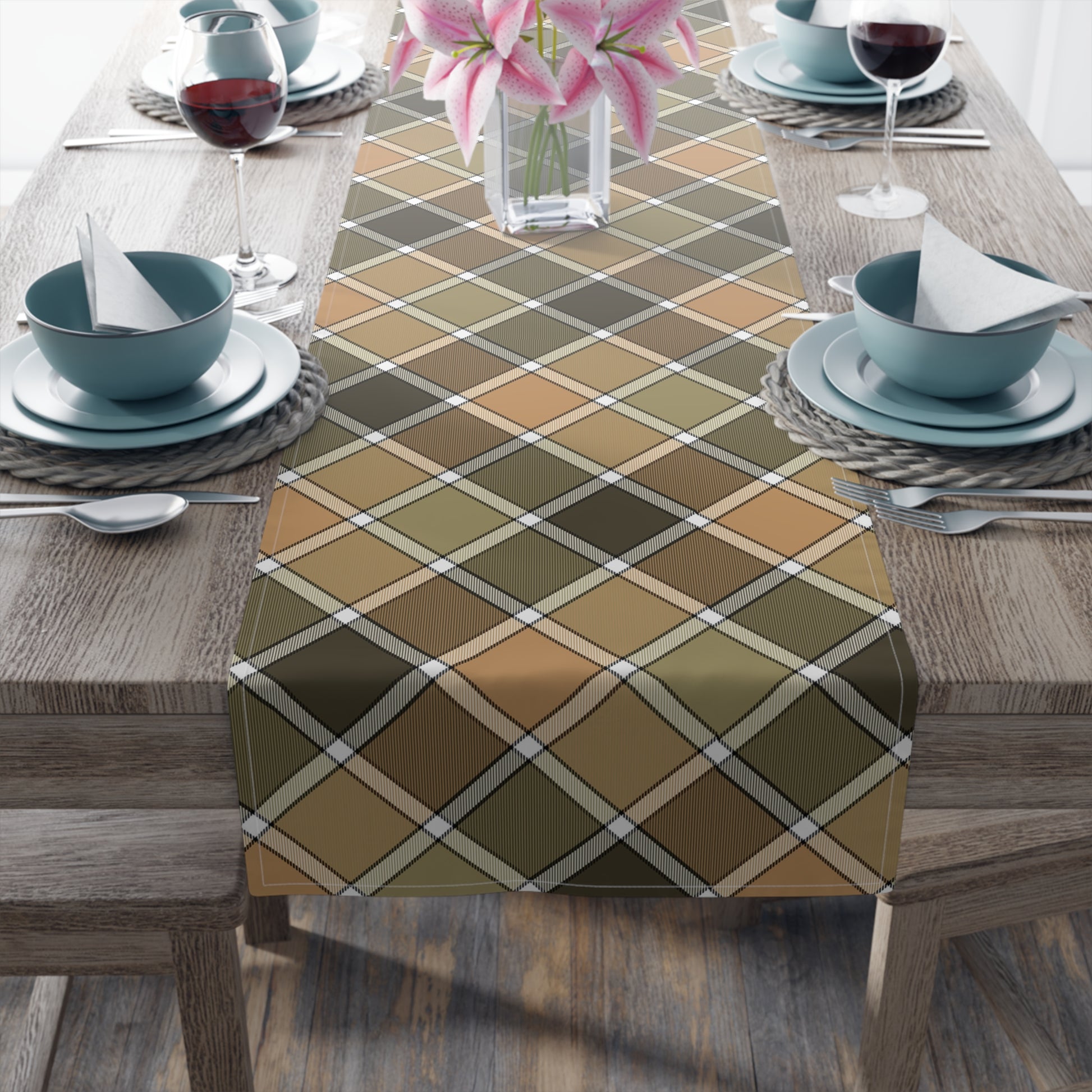 Our cotton twill Fall Plaid table runner has brown, green, orange patterned colors. The table runner is sitting table with blue dishes and flower vase.