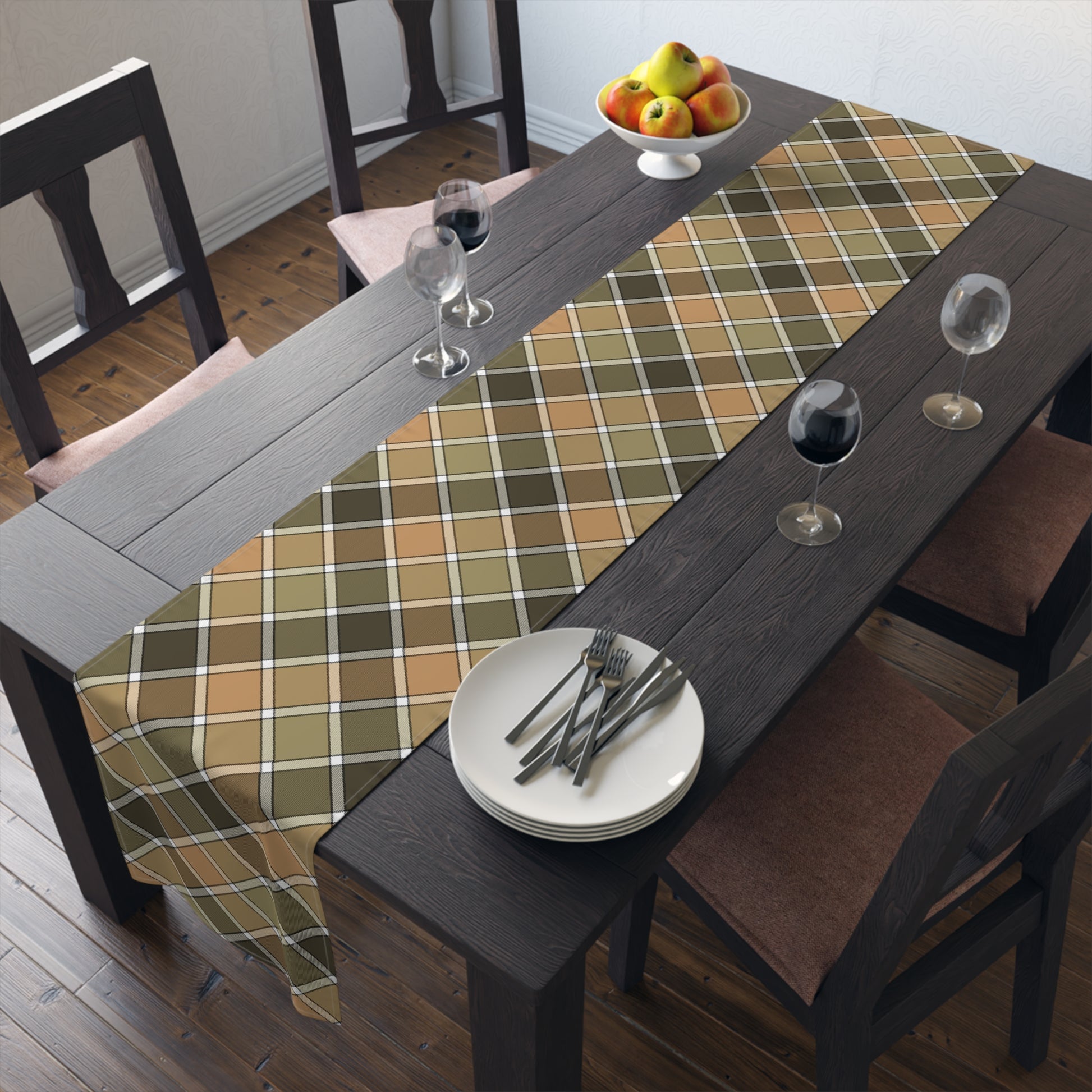 Our cotton twill Fall Plaid table runner has brown, green, orange patterned colors. The table runner is sitting on a table with plates, and glasses in a room setting.