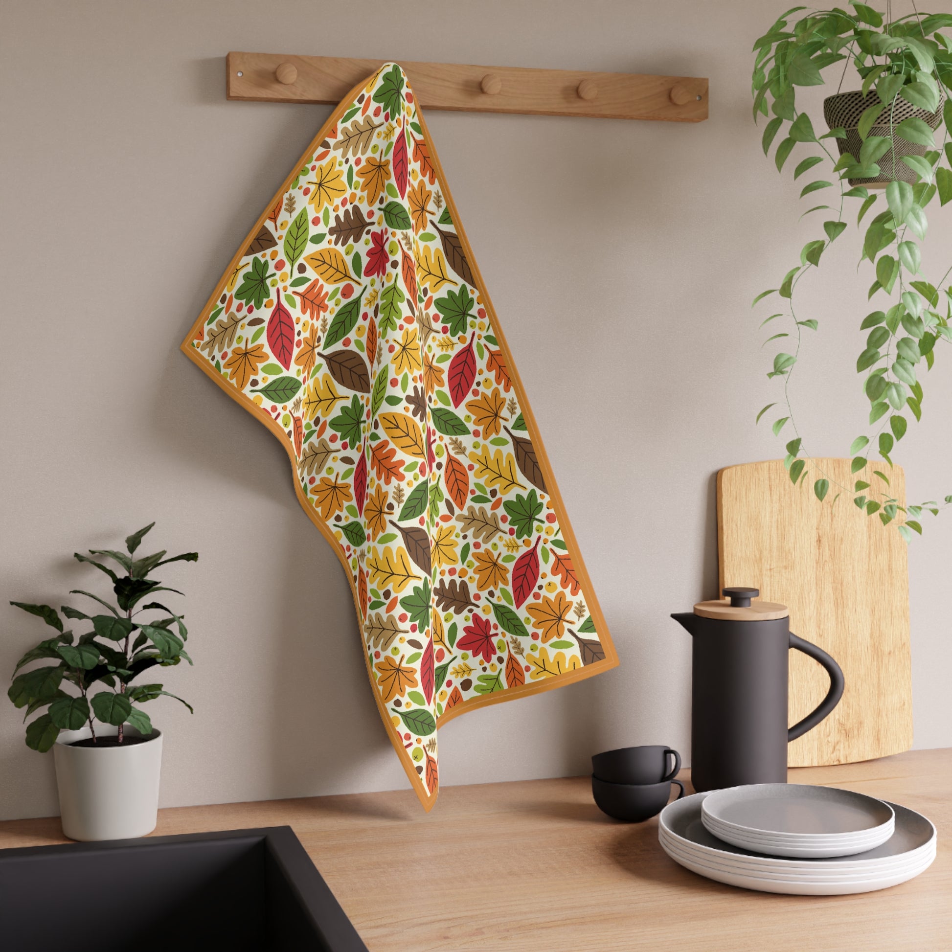 Colorful leaf-patterned towel hanging on a wooden rack with kitchen items below.