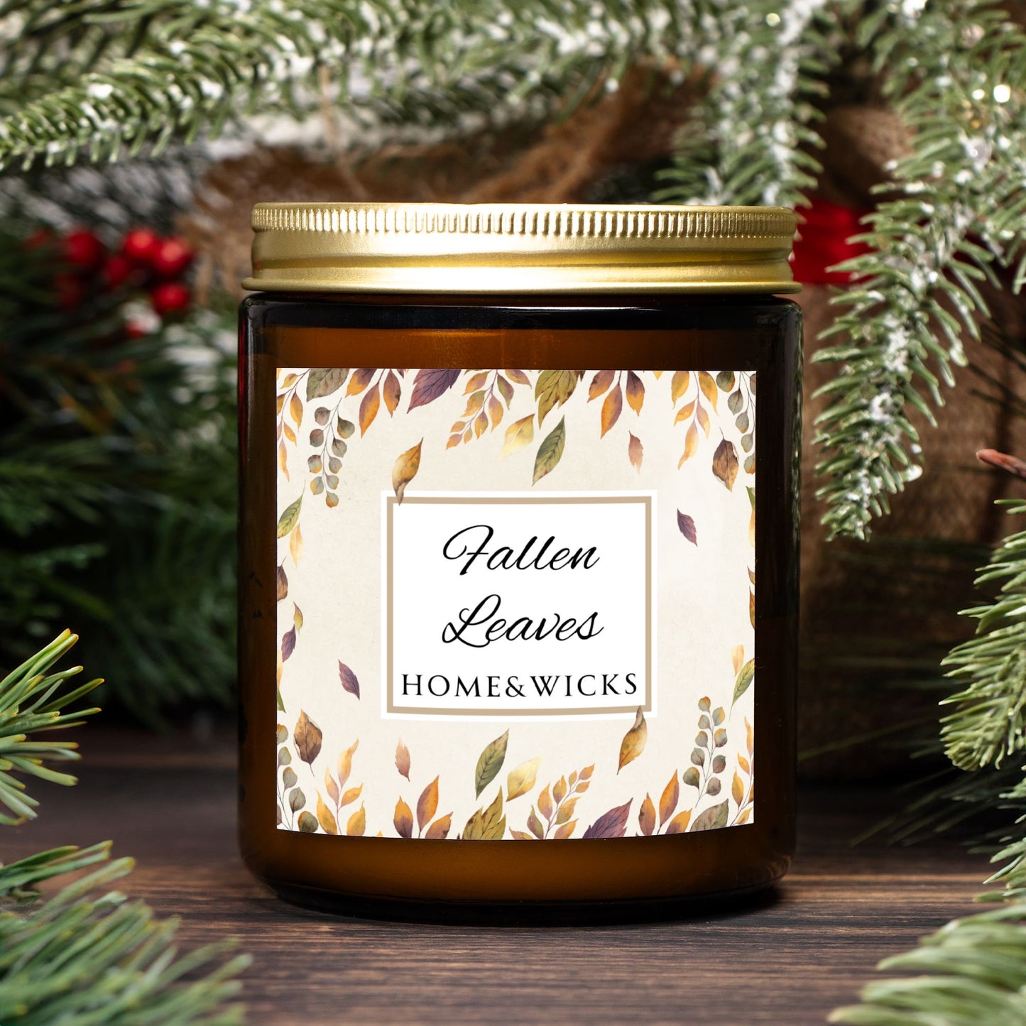 Candle in amber jar with gold lid and 'Fallen Leaves' label by Home & Wicks, surrounded by greenery
