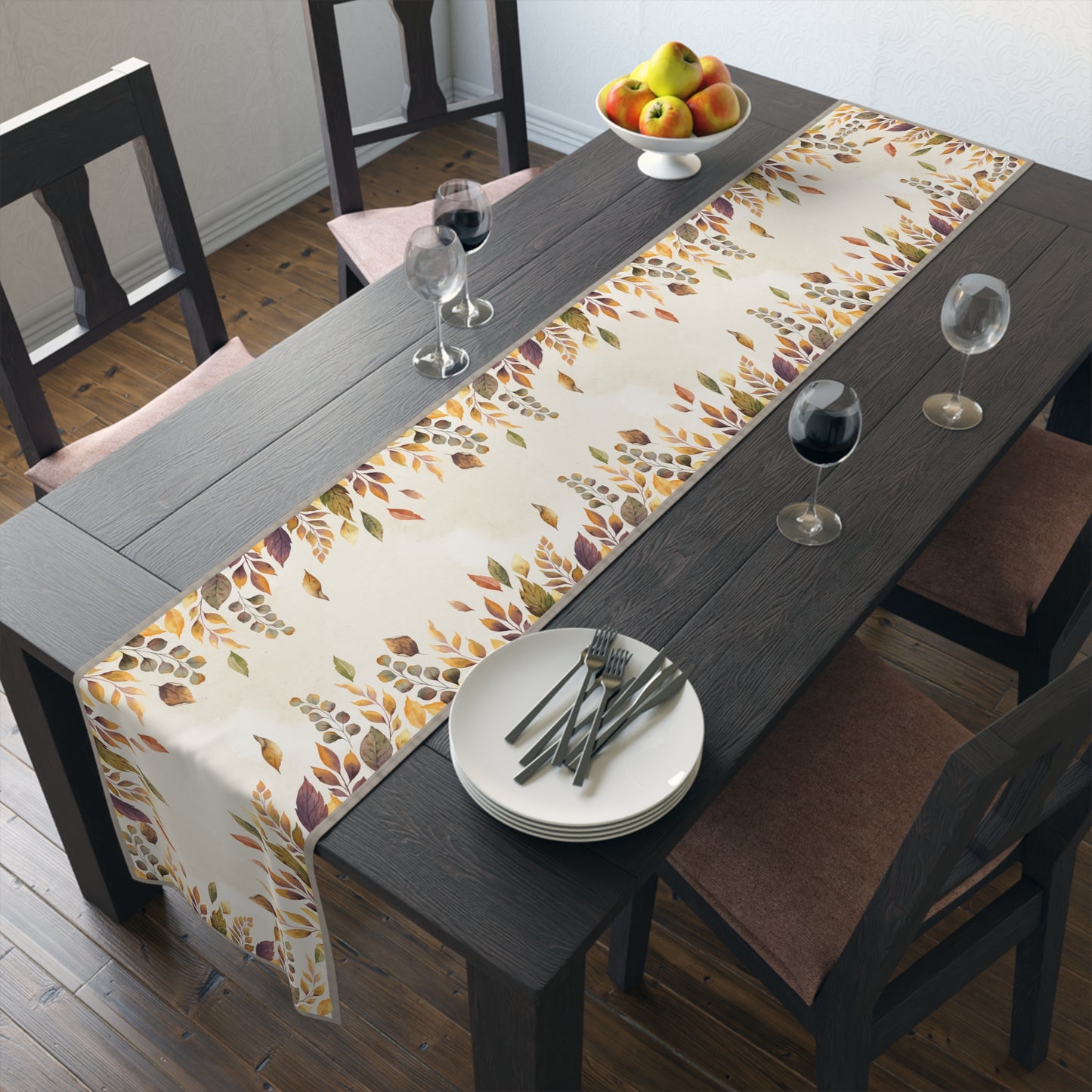 Dining table set with a fall-themed Fallen Leaves table runner, plates, and glasses.