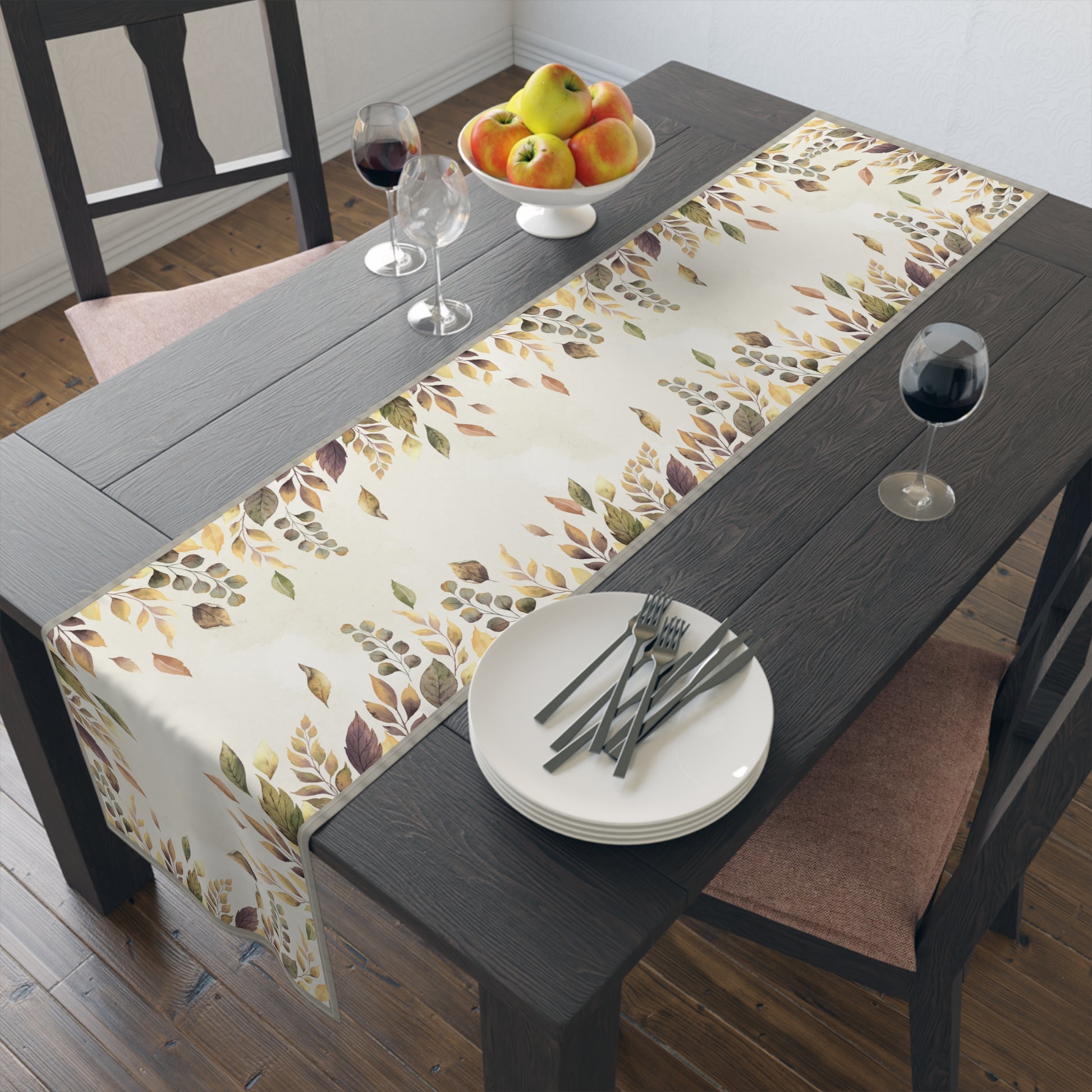 Dining table with a leaf-patterned table runner, plates, forks, and a fruit bowl.