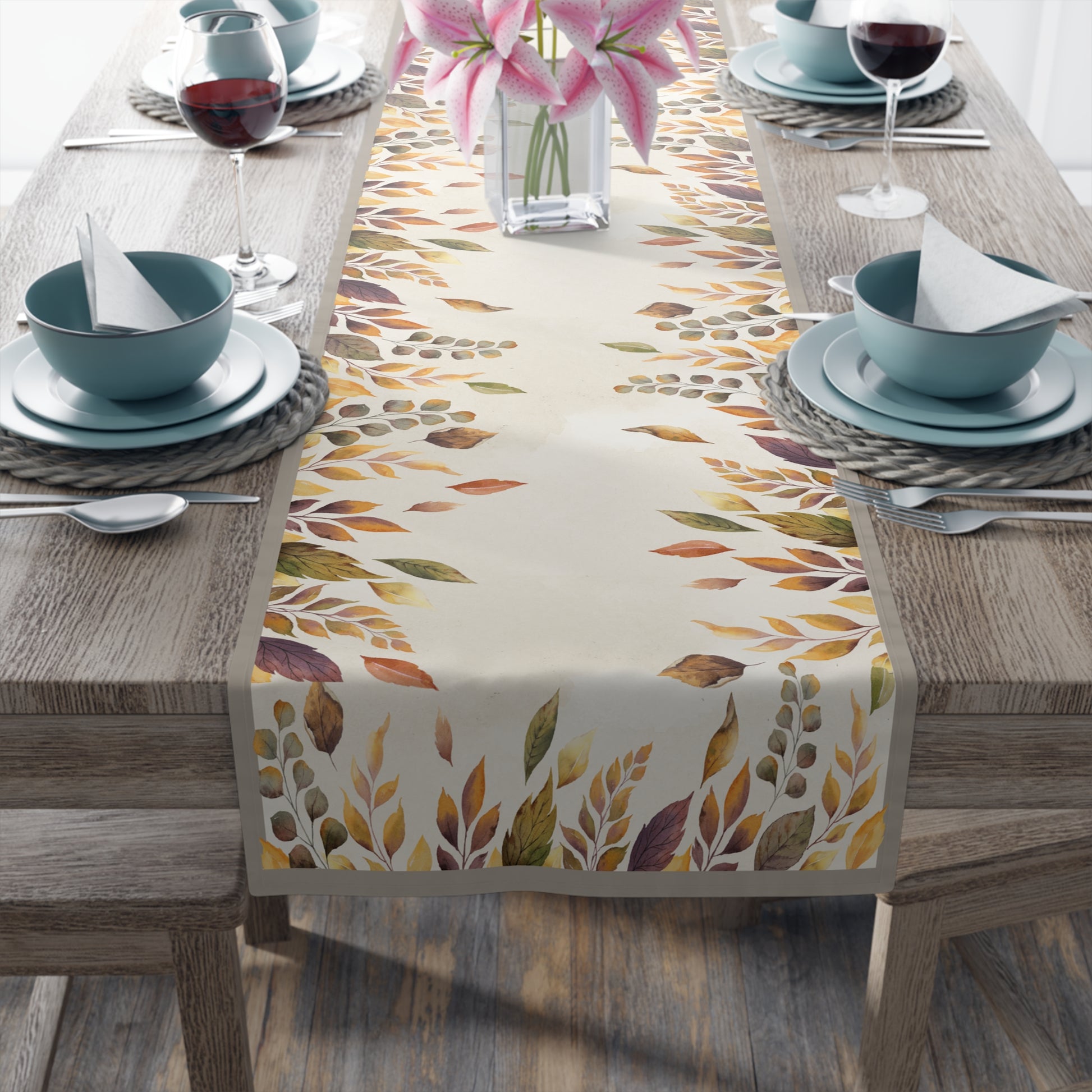 Table setting with a colorful leaf-patterned table runner on a wooden table.