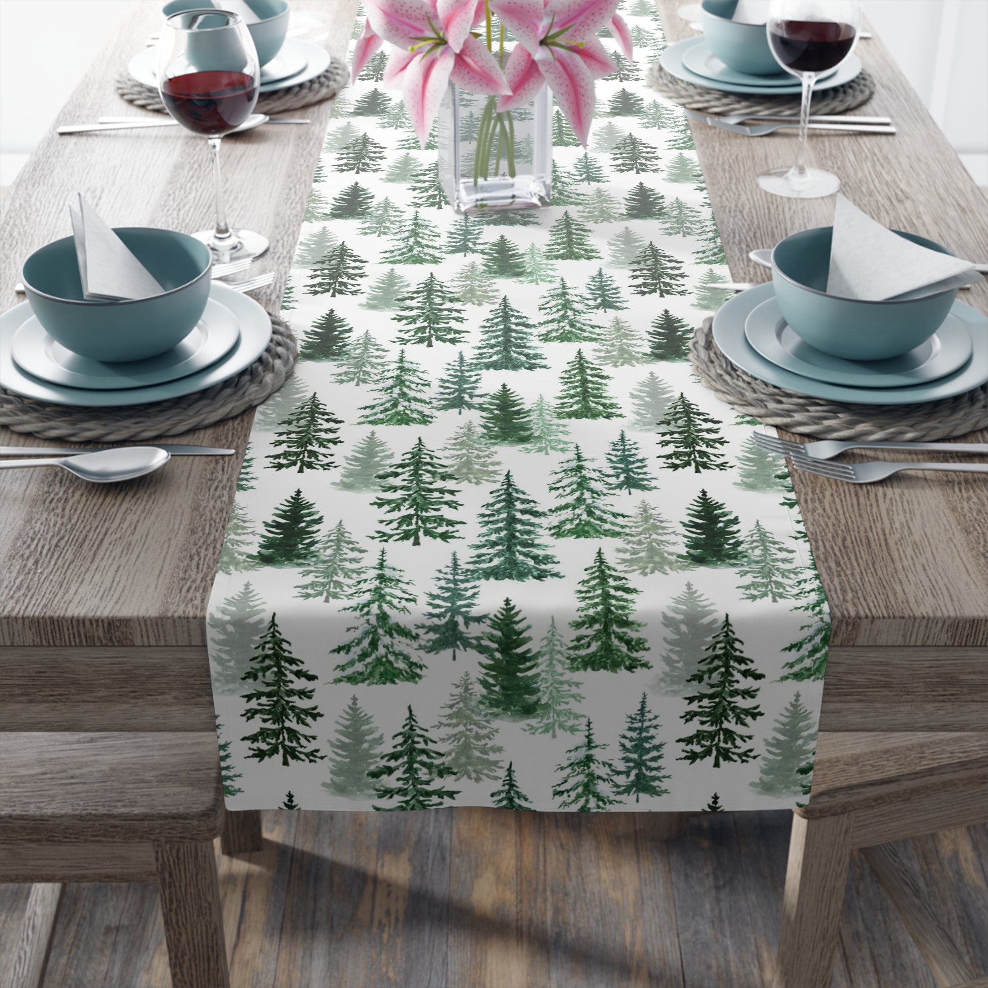 Table setting with a green and white forest-themed table runner on a wooden table.
