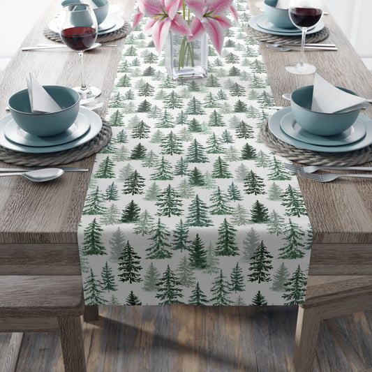 Table setting with a green and white forest-themed table runner on a wooden table.