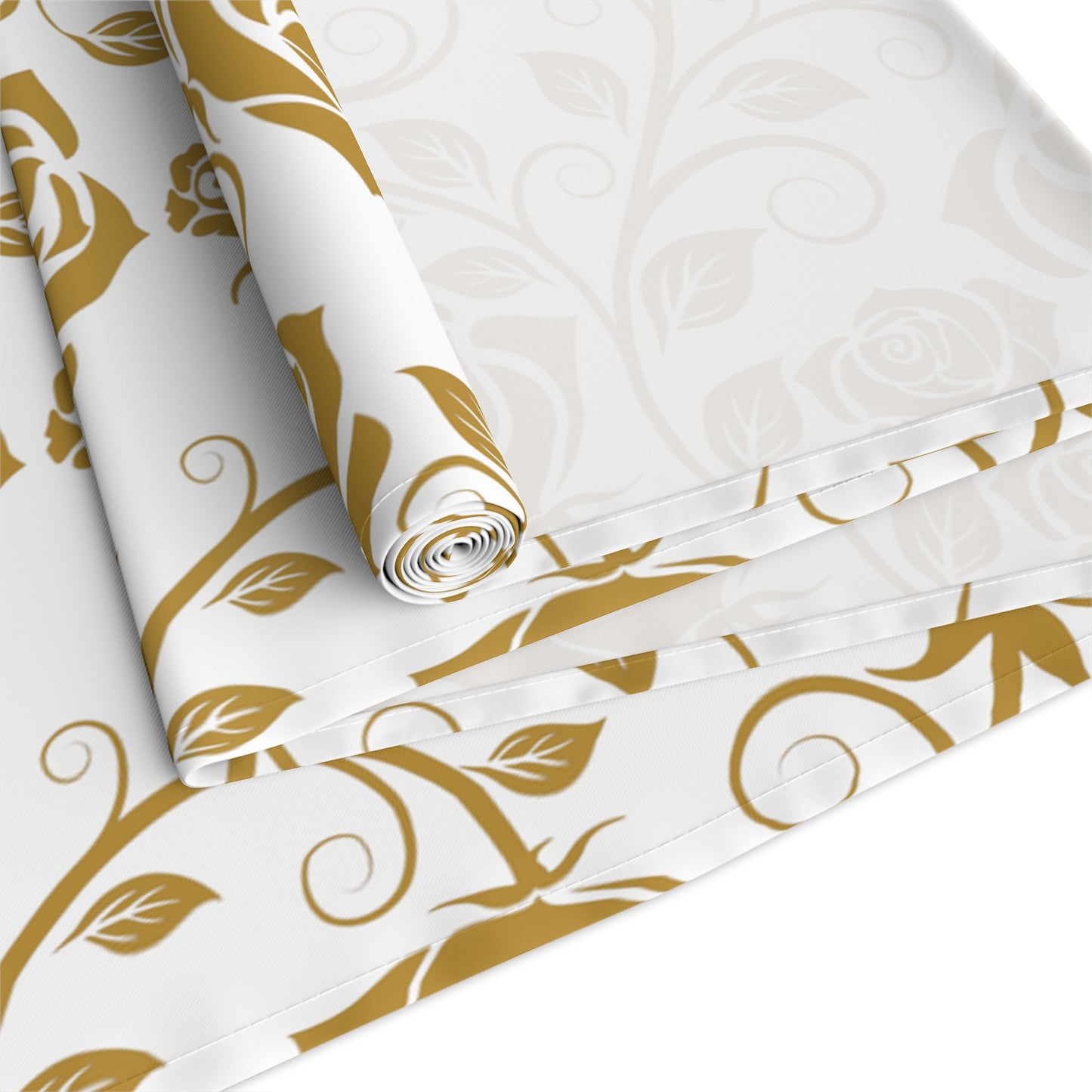 Table runner with gold floral pattern rolled up and folded on a white background