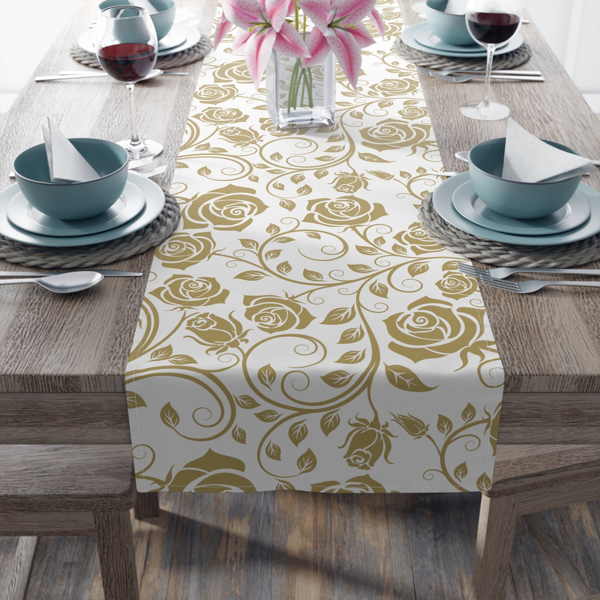 Table setting with a gold floral patterned table runner on a wooden table.