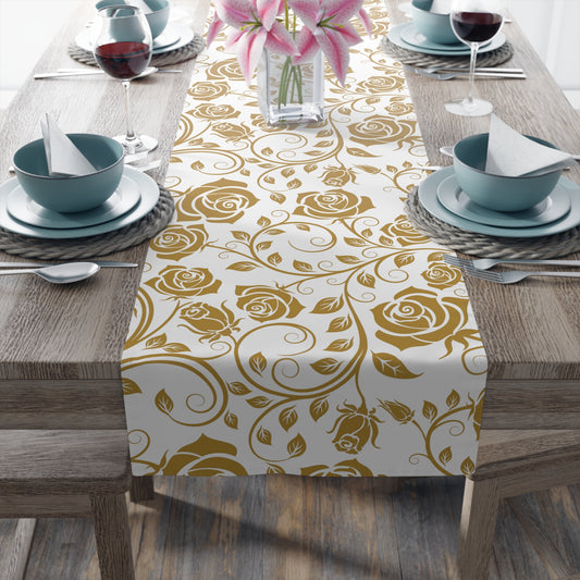 Table setting with a gold floral table runner on a wooden table.