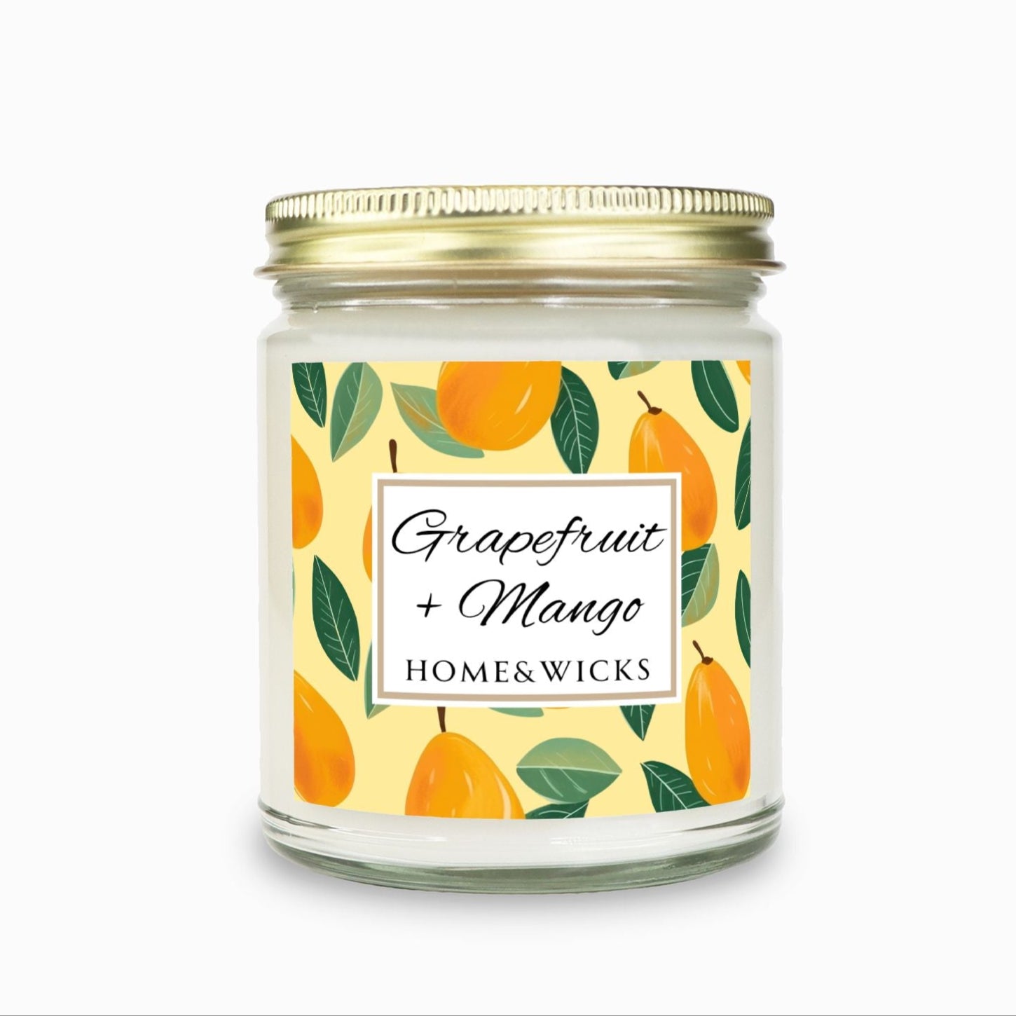 Grapefruit and Mango candle in a 9 oz. clear jar with gold lid and  a decorative mango label on a white background by Home & Wicks