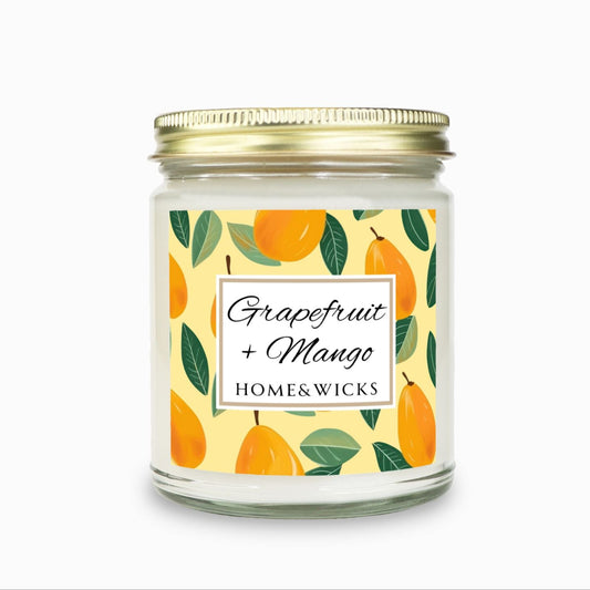 Grapefruit and Mango candle in a 9 oz. clear jar with gold lid and  a decorative mango label on a white background by Home & Wicks