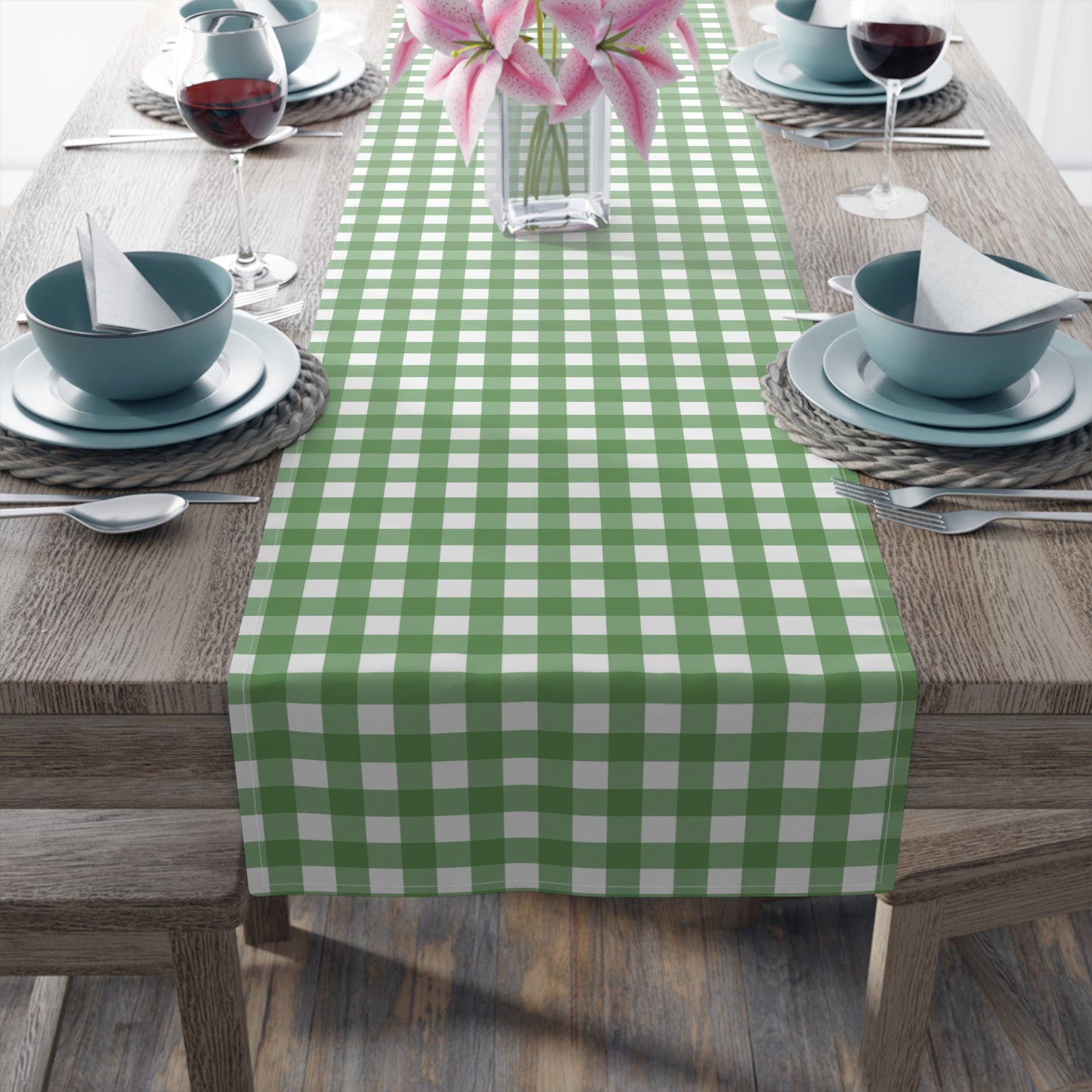 Green gingham checkered table runner with green and white gingham pattern printed on front of table runner, sitting on a wood table with place settings.